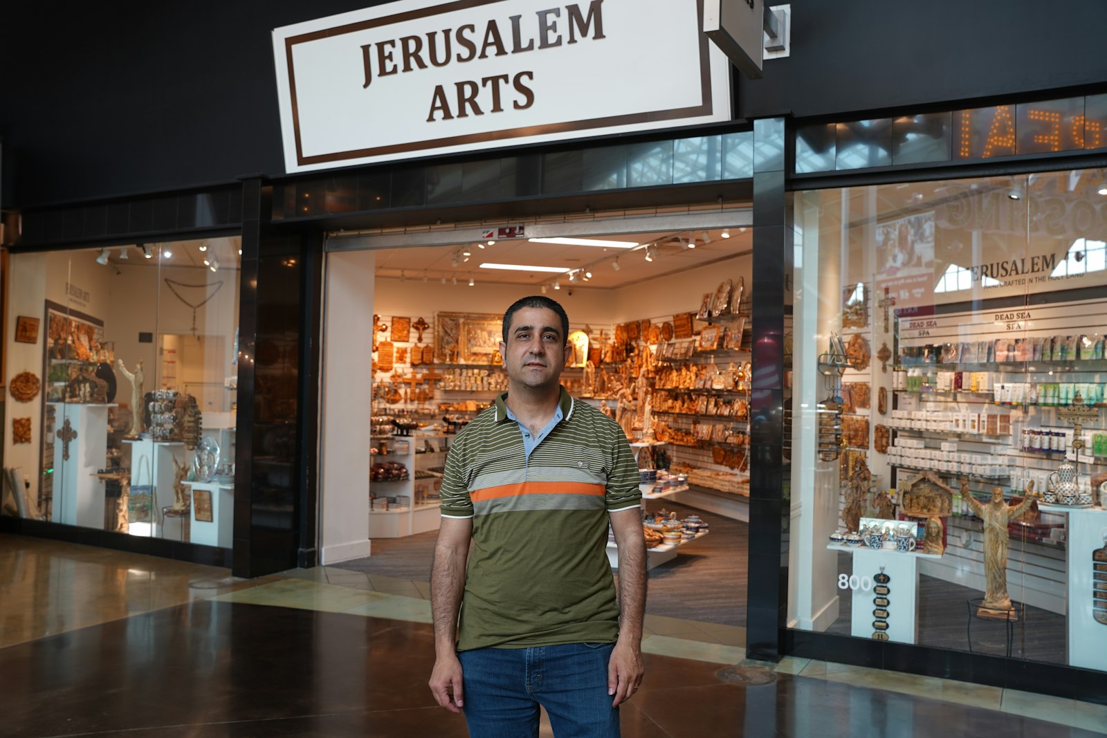 Husam Khair, owner of Jerusalem Arts at the Great Lakes Crossing Outlet Mall in Auburn Hills, stands in front of his store. Since opening the storefront in the mall in May 2023, Khair has seen an increase in foot traffic versus the kiosk he and his wife used to operate. Sales from the store go to support Christian families in Bethlehem.