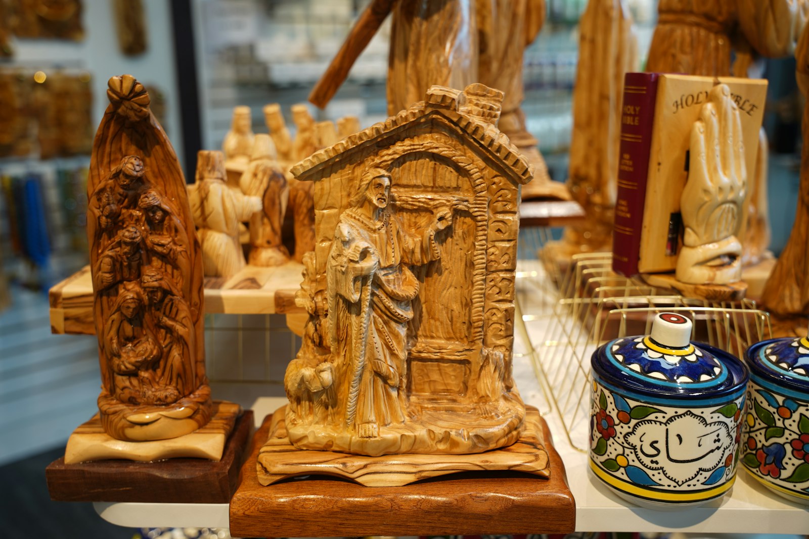 A carving of Jesus knocking at the stranger's door, one of many hand-carved items on sale at Jerusalem Arts. Khair explains that since the October 2023 Hamas attack and subsequent Israel-Hamas war, pilgrims have been unable to visit the Holy Land to purchase such items, making his store an economic lifeline for the Christian community in the Holy Land.