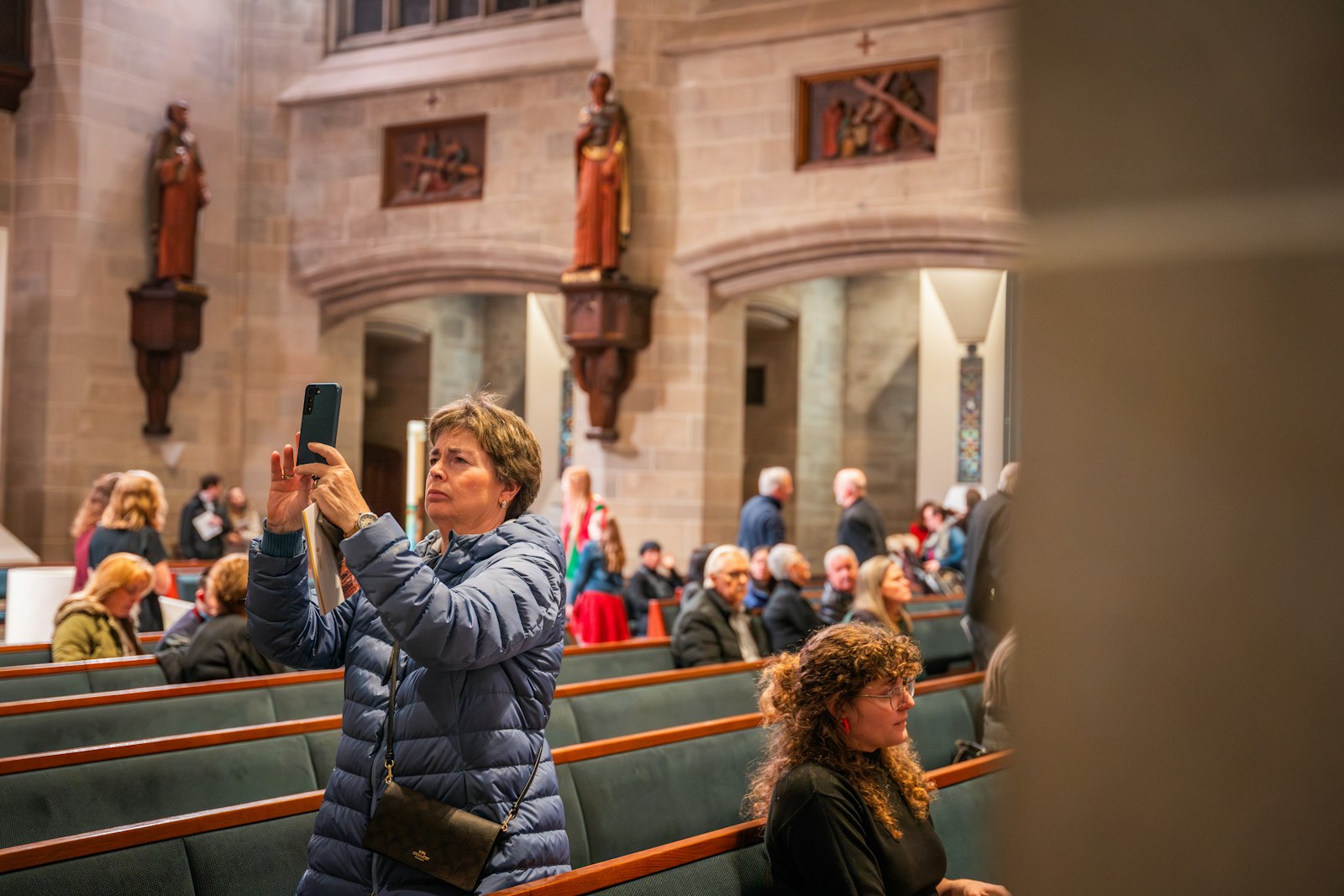 A woman takes a picture of one of the newly installed statues and relics. The "Journey with the Saints" pilgrimage will be permanently available for those who visit the cathedral, and those who experience miracles as a result of their prayers are invited to return to contribute to a planned new mosaic.