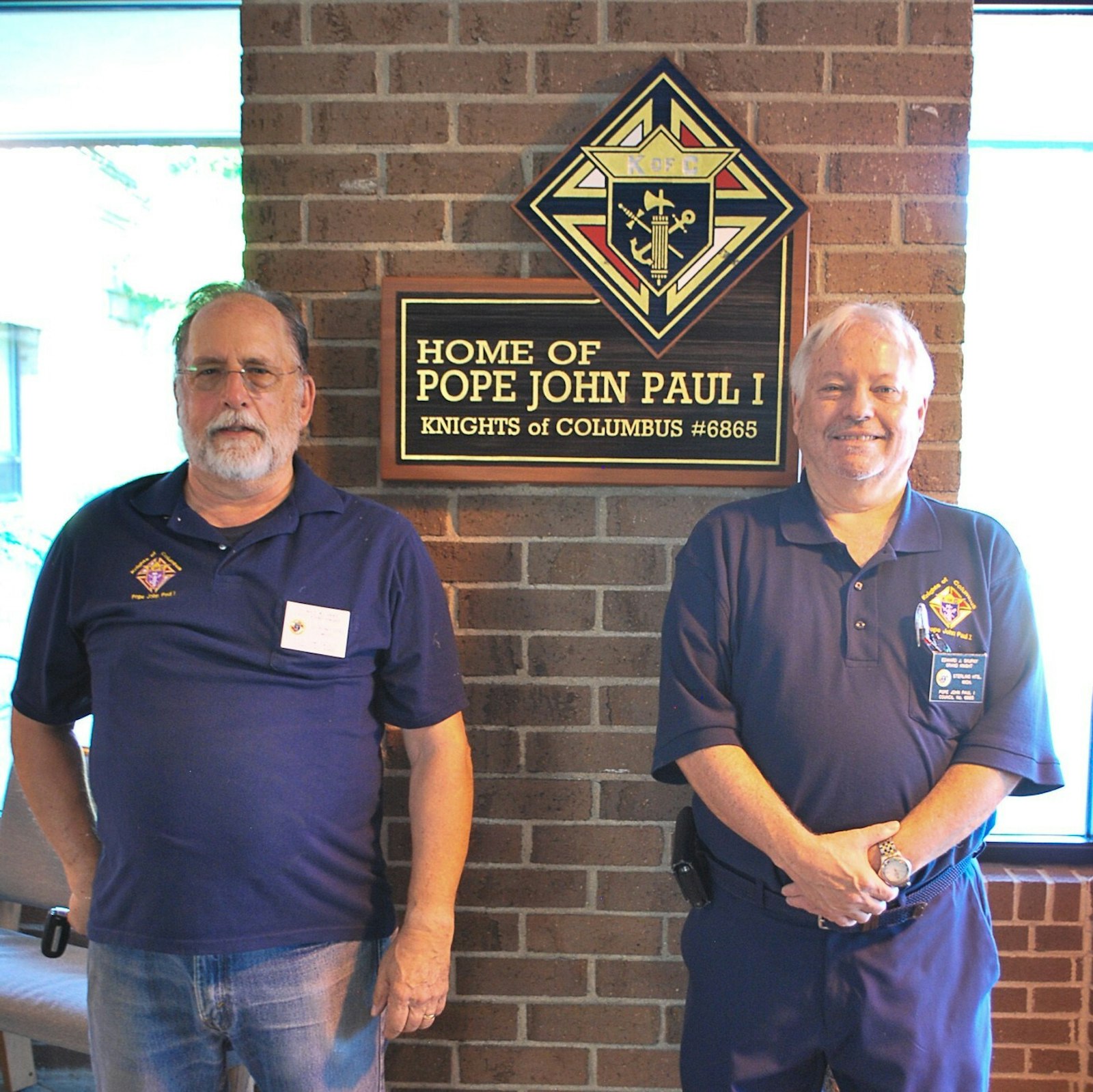 Tom Haas (left), previous Grand Knight of the Pope John Paul I Knights of Columbus Council No. 6865, and current Grand Knight Ed Skupny (right) stand by the sign bearing the name of “the smiling pope.” The council, based out of St. Blase Parish in Sterling Heights, will host a Spaghetti Dinner fundraiser on Sept. 24 dedicated to the soon-to-be beatified pope. (Courtesy of St. Blase Parish)