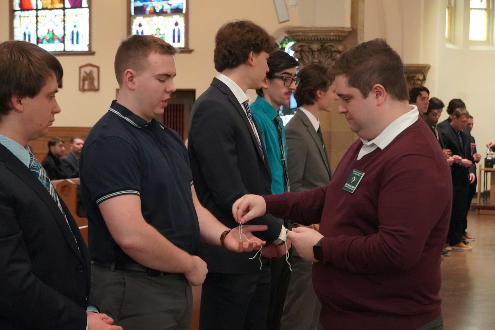 Matthew Salomons, coordinator of college councils for the Knights of Columbus Supreme Office, hands each of the men enrolling in the Knights of Columbus a string as part of the order's exemplification ceremony at Our Lady of the Rosary Church in Detroit on Feb. 1. Now more than ever, young men need formal groups like the Knights of Columbus to encourage fraternity among Catholic men in an increasingly secular world, Salomons said.