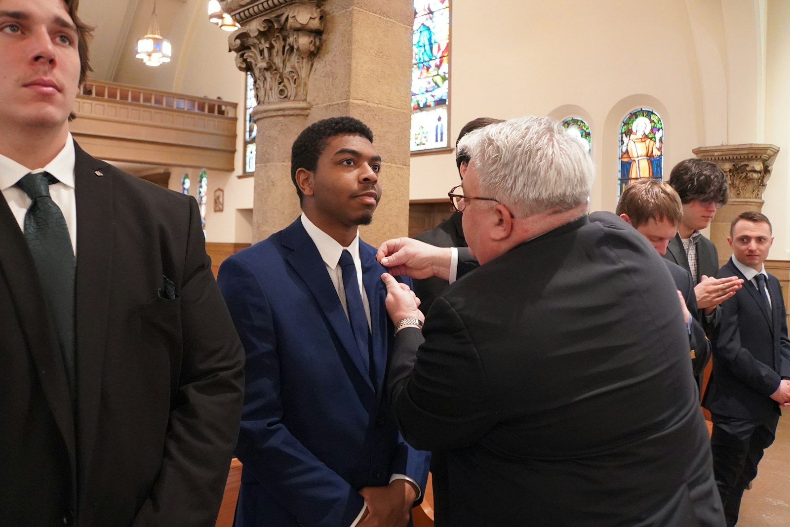 Christopher Kolomjec, former state deputy for the Michigan Knights of Columbus, pins a Knights of Columbus membership pin on each of the newest members of the Blessed Carlo Acutis Council. During the exemplification ceremony, the new members were granted the rank of third-order Knights.