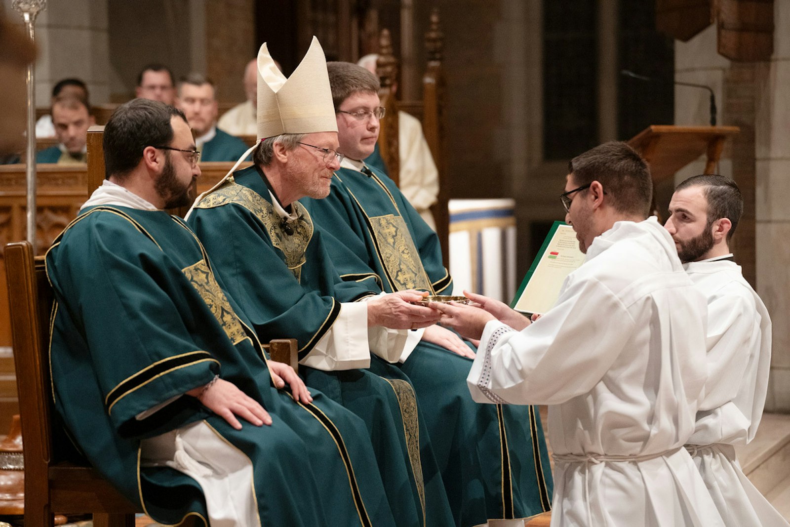 Gaylord Bishop Jeffrey J. Walsh, left, offers a paten to third-year seminarians being installed in the ministry of acolyte Nov. 8 at Sacred Heart Major Seminary.