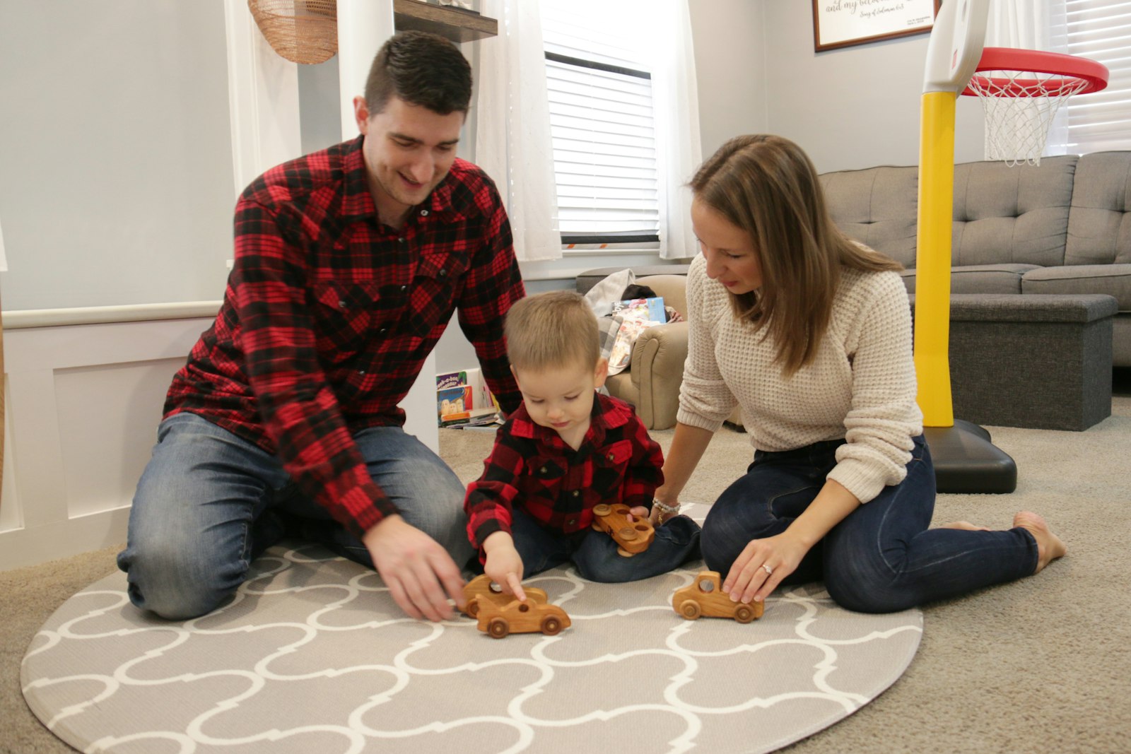 Joe and Alexandria Staniszewski play with John Paul and the toy wooden cars Joe had built for The Lion and the Lamb, LLC.