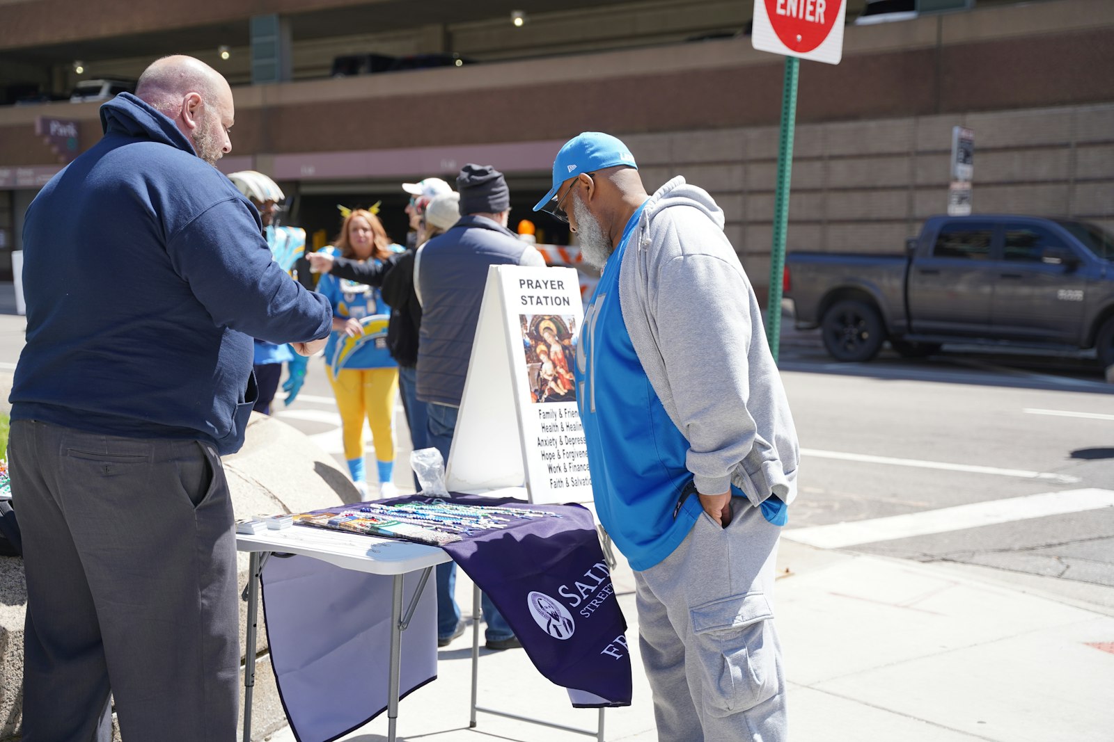 A Detroit Lions fans scouts the St. Paul Street Evangelization table that has rosaries, miraculous medals and prayer cards. Evangelists were on hand to talk about Jesus, Catholicism and make friends with passersby.