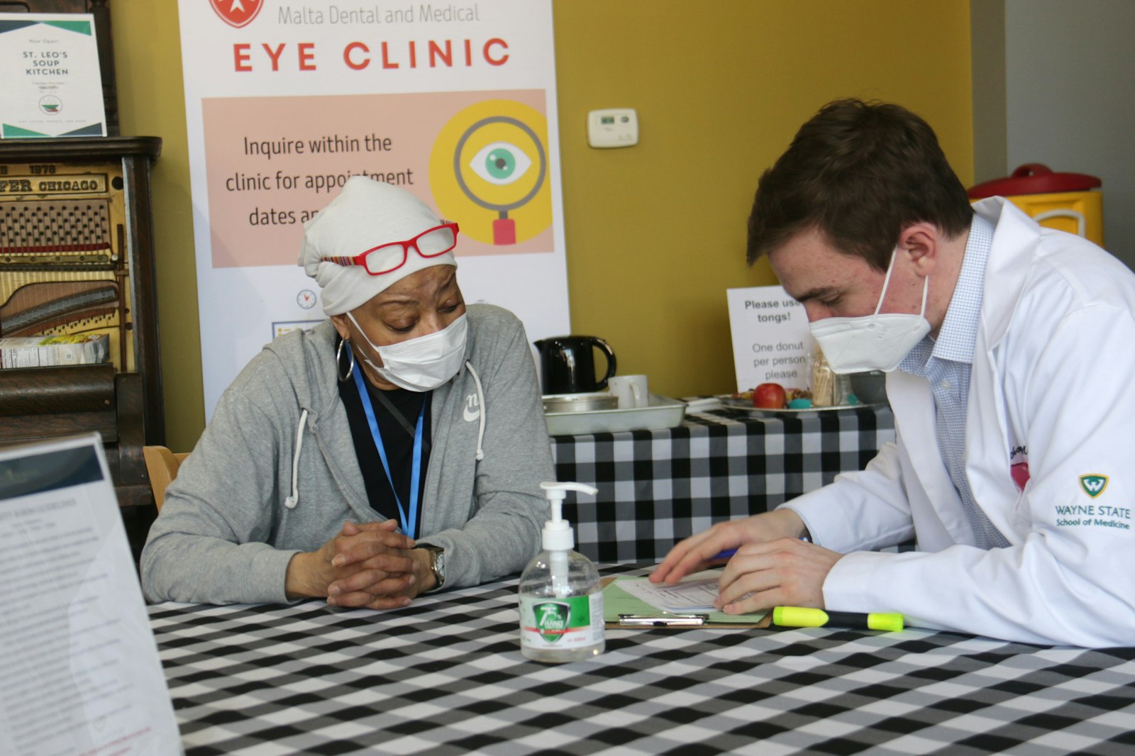 Anthony Mrocko examines Cathryn Anderson's medical history before her appointment at the Malta Eye Clinic at the Catholic Charities of Southeast Michigan Center for the Works of Mercy. The eye clinic will be open once a month, providing free eye care to low-income individuals.