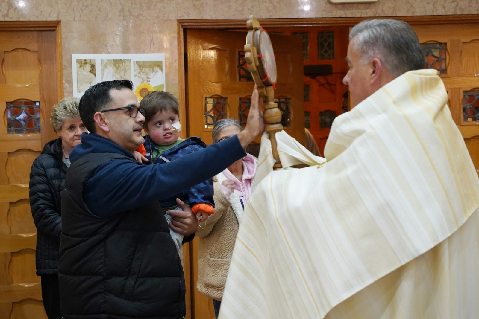 Mario Gonzalez holds up his son, Damien, to the relic of St. Padre Pio, held by Fr. Zbigniew Grankowski of St. Barbara Parish in Dearborn. Damien had open-heart surgery six weeks ago and spent a month in the hospital. His family came to St. Barbara Parish on Nov. 17 to ask for the intercession of St. Padre Pio in praying for his healing. Mario reports Damien has been doing well since the procedure. (Daniel Meloy | Detroit Catholic)