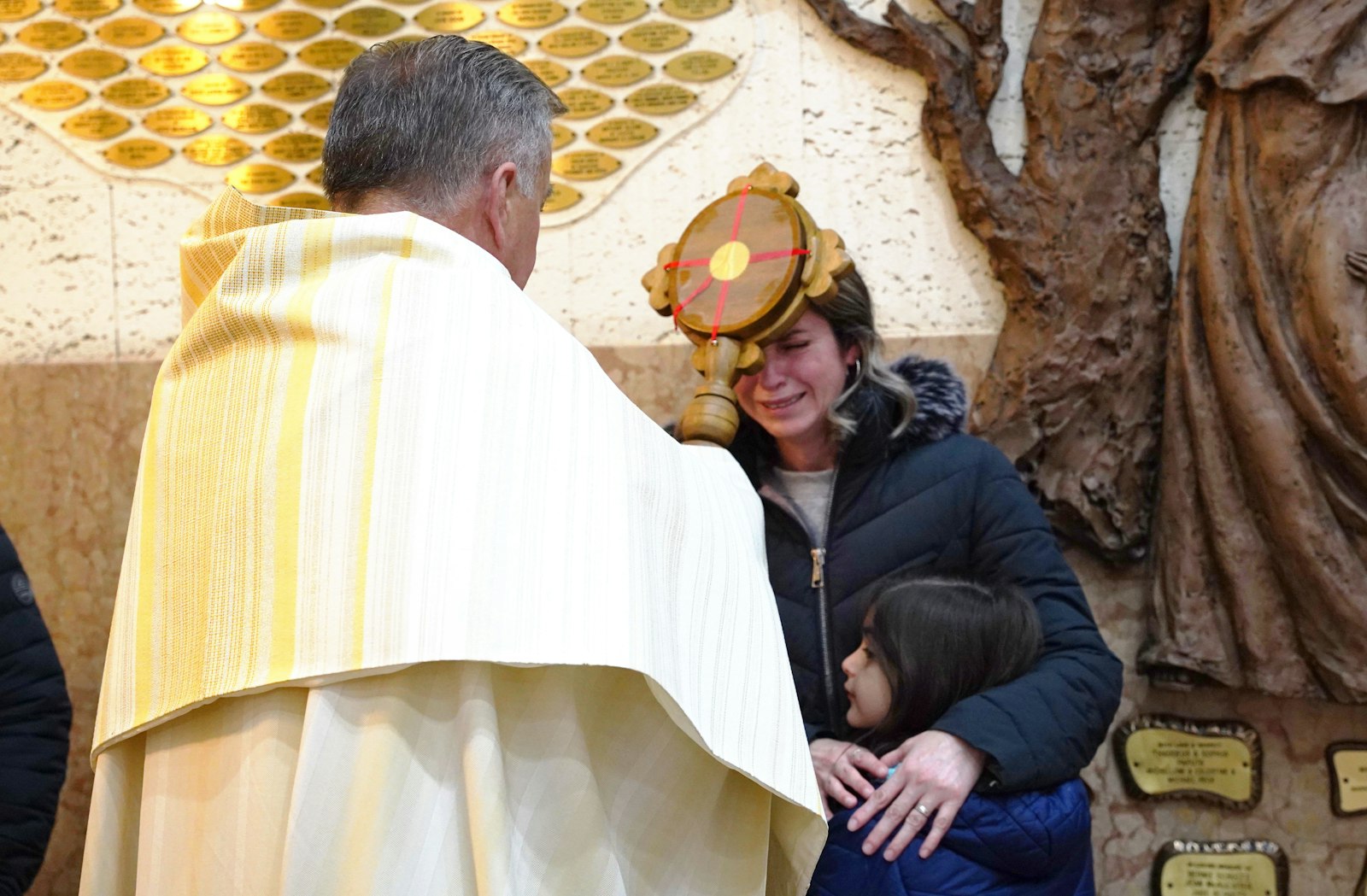 Fr. Grankowski of St. Barbara Parish blesses Mary Lou Lopez with the relic of St. Padre Pio. Mary Lou Lopez's son, Damien, recently had open-heart surgery, so the family came to St. Barbara Parish to pray for St. Padre Pio's intercession. (Daniel Meloy | Detroit Catholic)