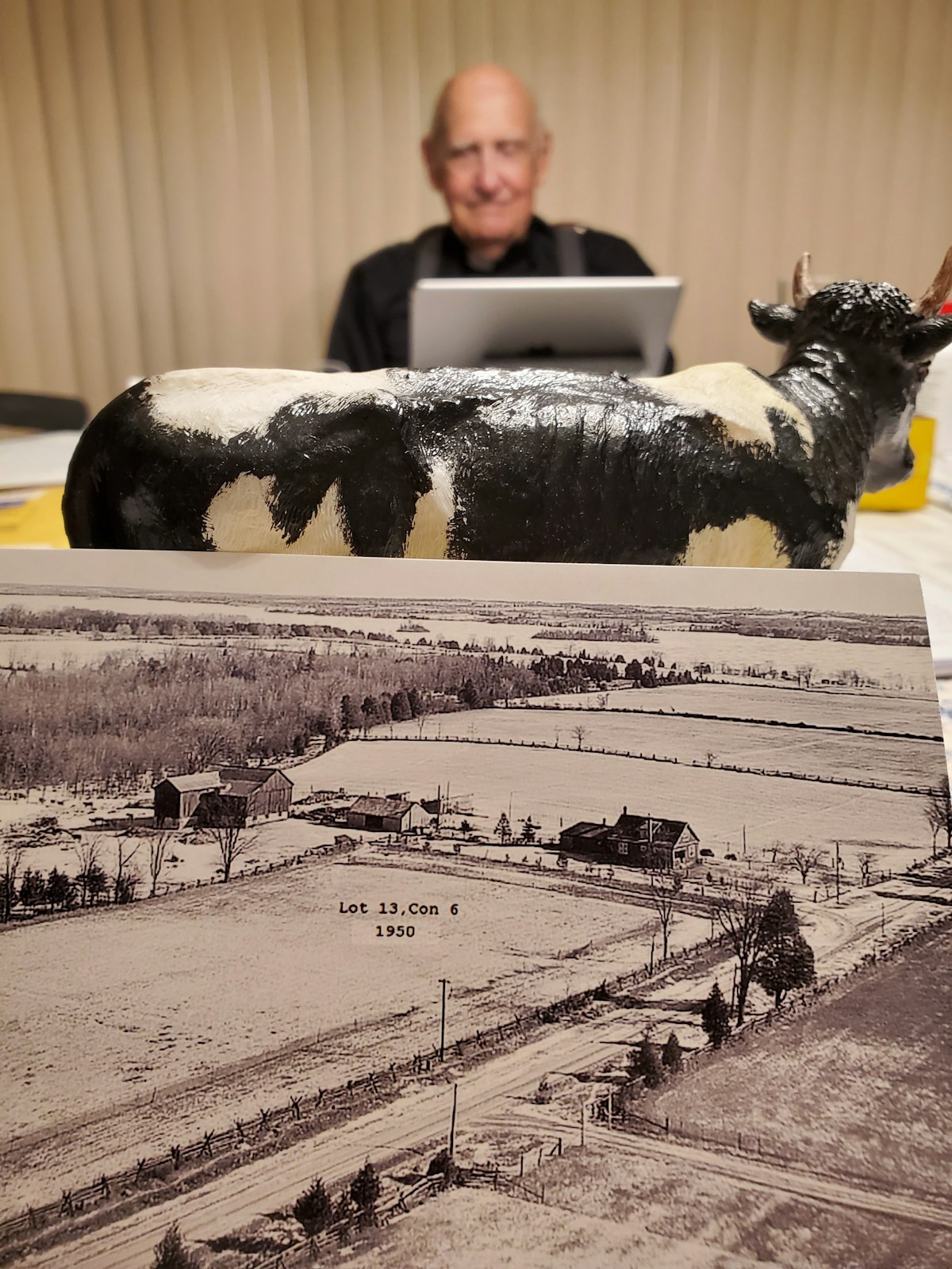 A photo of the family farm in Ennismore, Ontario and a cow figurine are in the foreground. Msgr. Moloney said while visiting Ennismore, a cow came up and licked him in the face, which he knew was God's ways of saying he was supposed to go to the seminary. (courtesy photo)