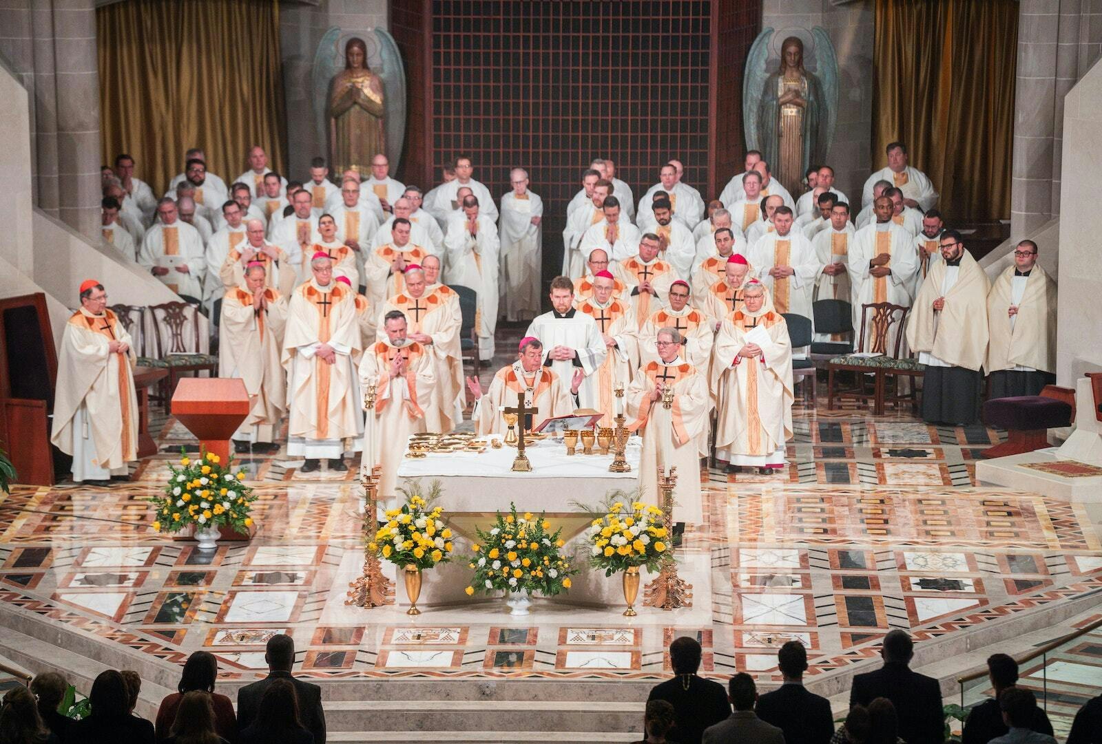 El Arzobispo Allen H. Vigneron, rodeado de obispos, sacerdotes y diáconos de la Arquidiócesis de Detroit, ofrece la Sagrada Eucaristía al final de la Misa. El Obispo Monforton prometió fidelidad al liderazgo del Arzobispo Vigneron en la arquidiócesis y dijo que espera con ilusión servir junto a los otros obispos auxiliares de Detroit.