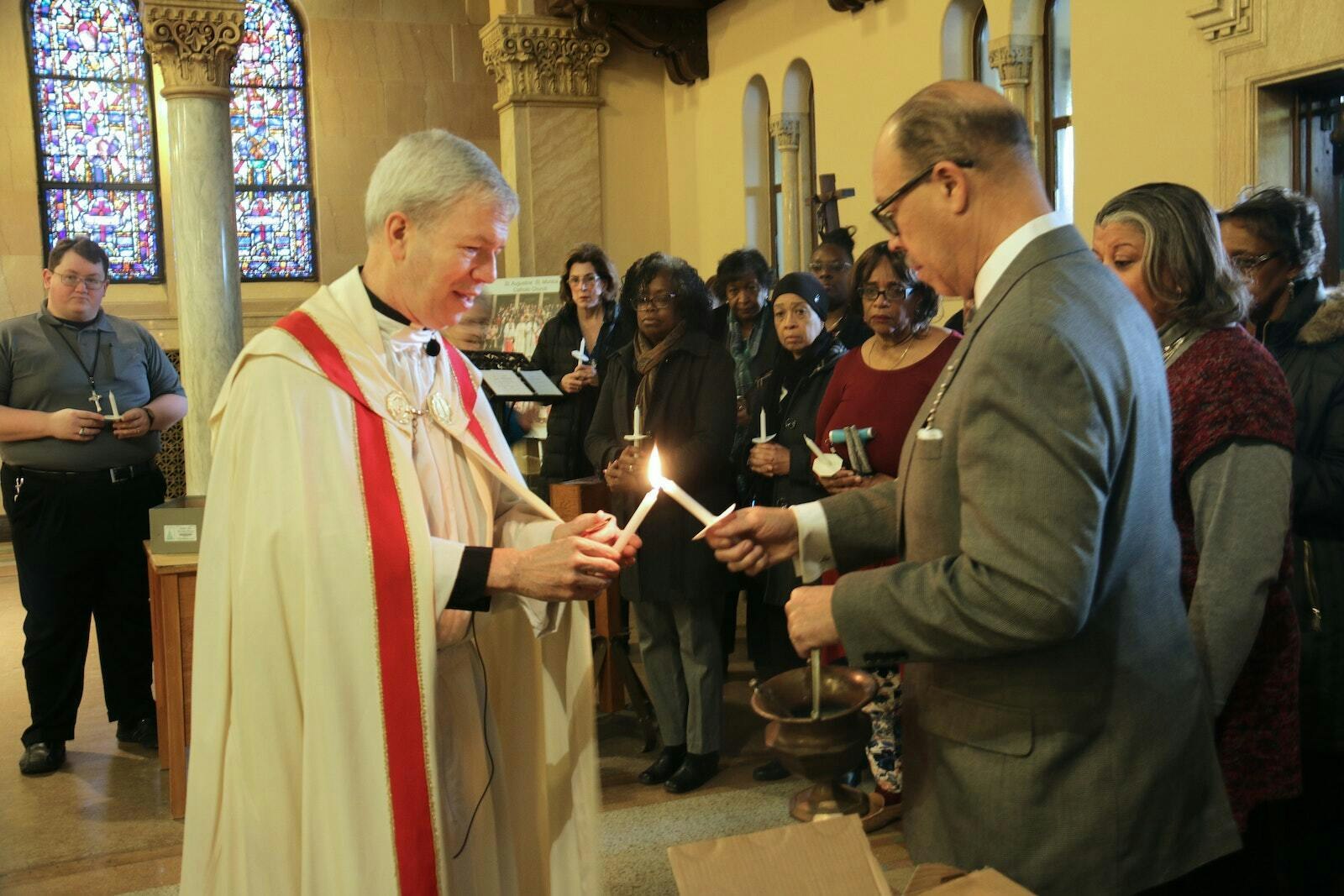 Msgr. Trapp lights a candle before the Candlemas procession at St. Augustine and St. Monica Parish in February 2019. The parish hosted the first of four talks in the Disciples of Mission speaker series, a cooperative mission between Sacred Heart Major Seminary and the Archdiocese of Detroit's Office of Black Catholic Ministry. (Daniel Meloy | Detroit Catholic)