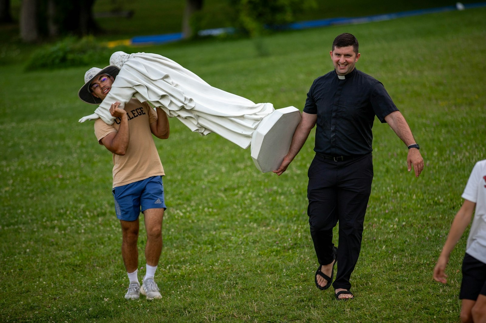 Fr. John Jaddou, a priest of the Chaldean Eparchy of St. Thomas the Apostle, helps a volunteer carry a statue of Jesus across the grounds during a summer camp activity in 2024. (Courtesy of Our Lady of the Fields Camp)