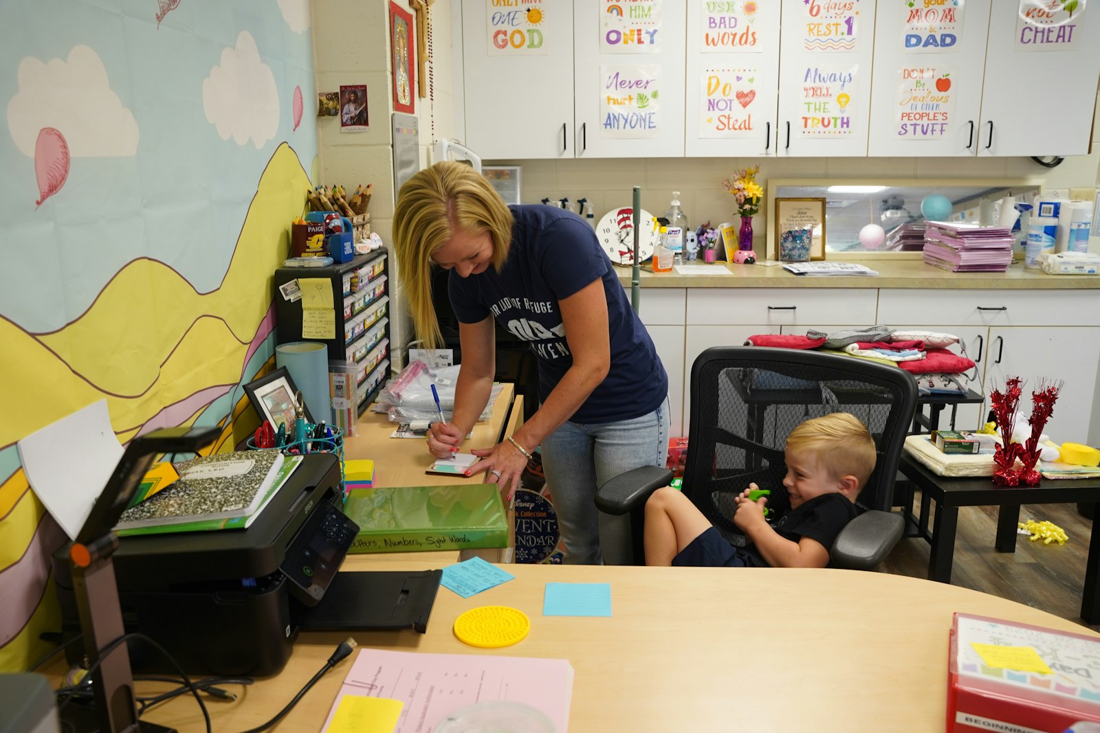 Leo cleans up her desk as she gets ready for the school year as her son, Lane, looks on. Paige and Leo were both baptized this Easter vigil.