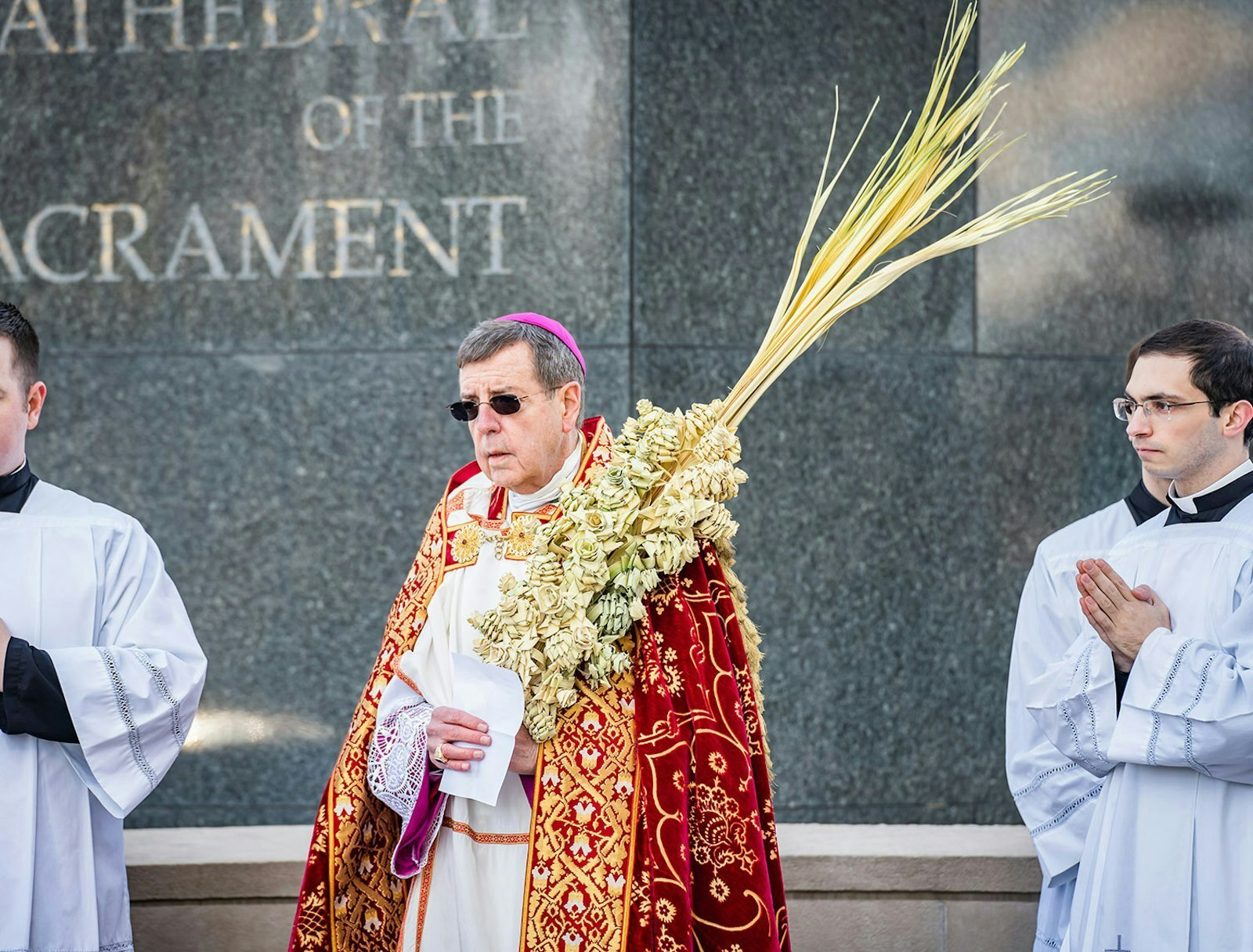 Archbishop Allen H. Vigneron carries a palm frond weaved by Tony Wenson during last year's Palm Sunday liturgy at the Cathedral of the Most Blessed Sacrament in Detroit. (Valaurian Waller | Detroit Catholic)