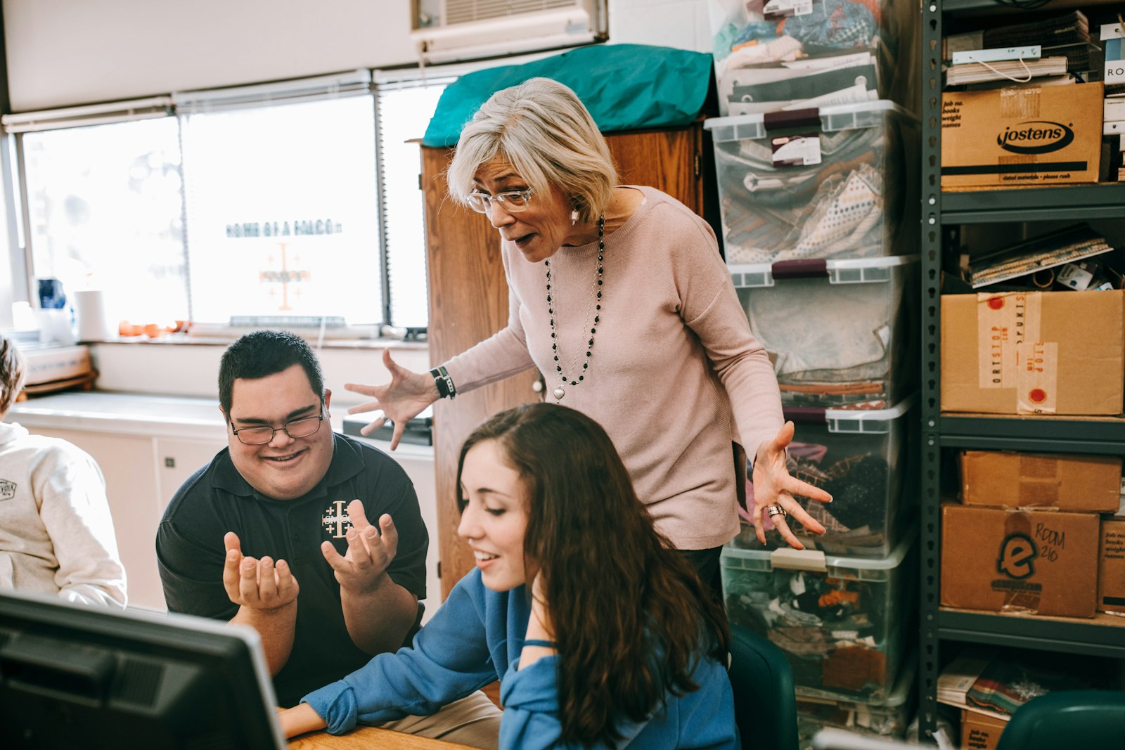 St. Mary Catholic Central sophomore (at the time) Jacob Goda works on the yearbook staff with the assistance of Katie Raymond and teacher Nancy Masuda in 2018. Goda is a graduate of St. Mary's St. Andre Bessette Open Door Inclusion Program, which serves students with special learning needs. (Naomi Vrazo | Detroit Catholic)