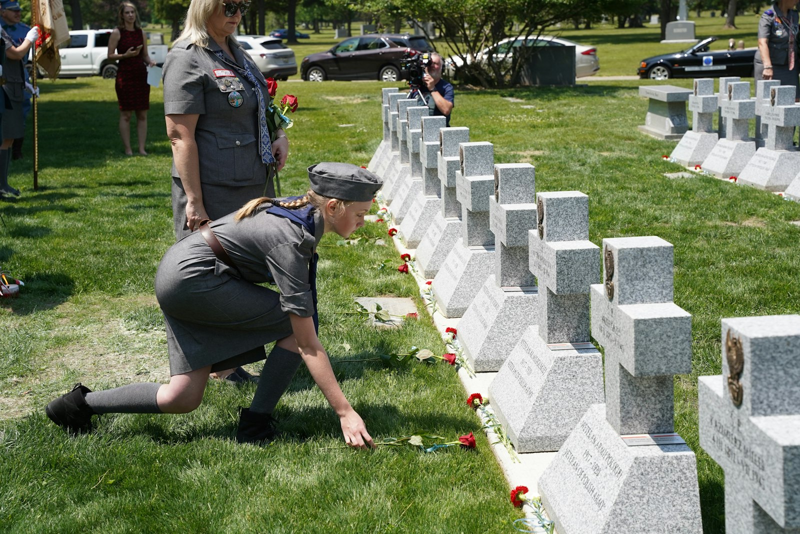 Polski harcerz składa kwiaty pod nowymi nagrobkami weteranów Wojska Polskiego na Cmentarzu Zmartwychwstania Pańskiego podczas ich poświęcenia 17 czerwca.