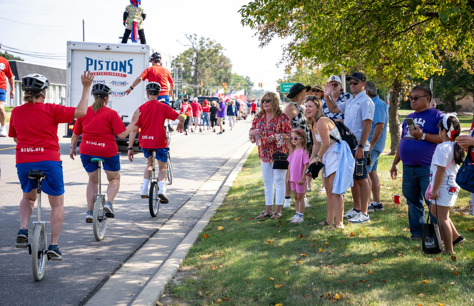 Spectators wave and cheer as unicycles ride past as part of the Poland Day 2024 parade.