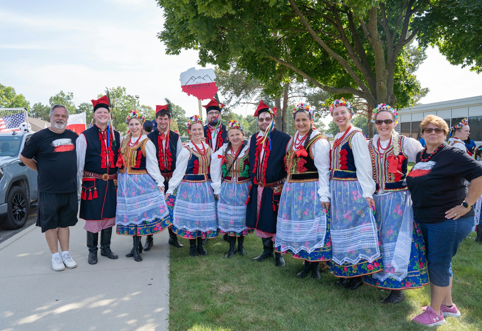 The Zakopane Dancers, dressed in traditional Krakowiak costumes, with women in floral-pattern skirts and men donning dark trousers. The Krakowiak is the traditional national dance costume of Poland.