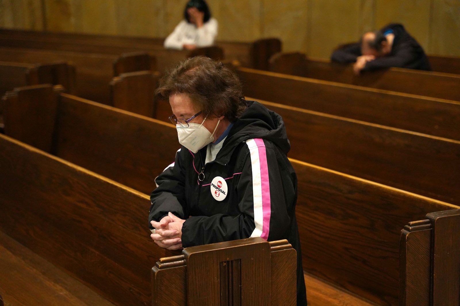 A woman wearing a "No on Proposal 3" button bows her head in prayer at the National Shrine of the Little Flower Basilica in Royal Oak.