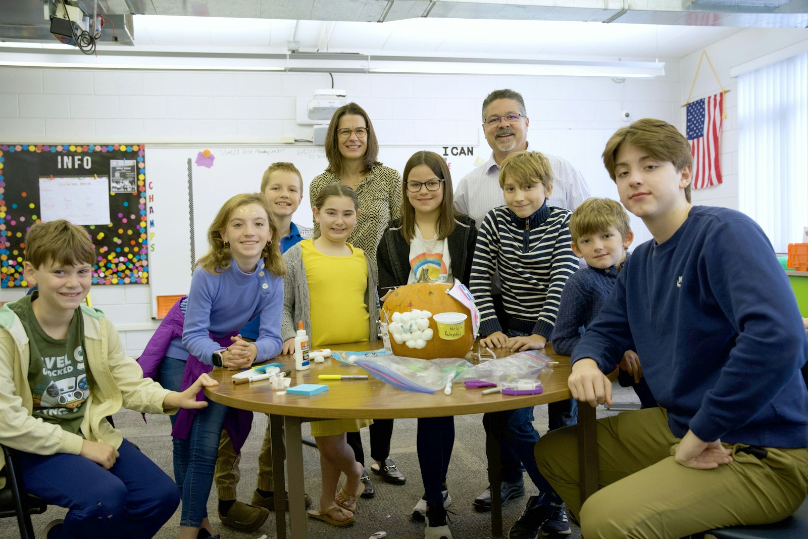 Fourth-graders stand around their pumpkin rendition of St. John of God. The students included different symbols to represent aspects of the saint's life.