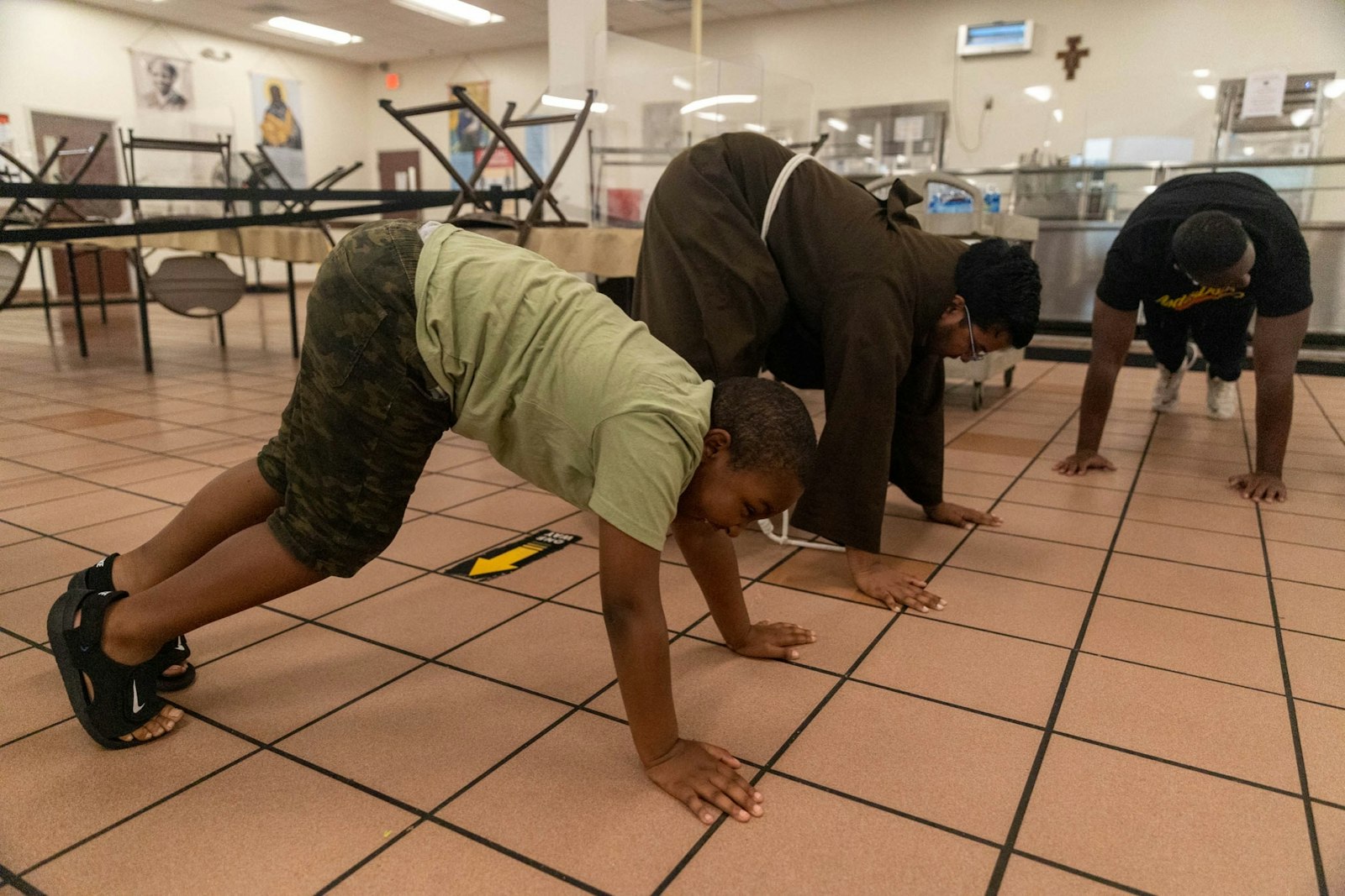 Friars, campers and counselors do push-ups during a group activity as part of the Rosa Parks Summer Peace Camp at the Capuchin Soup Kitchen. The camp allows kids to develop healthy habits, practice interacting with others and have fun.