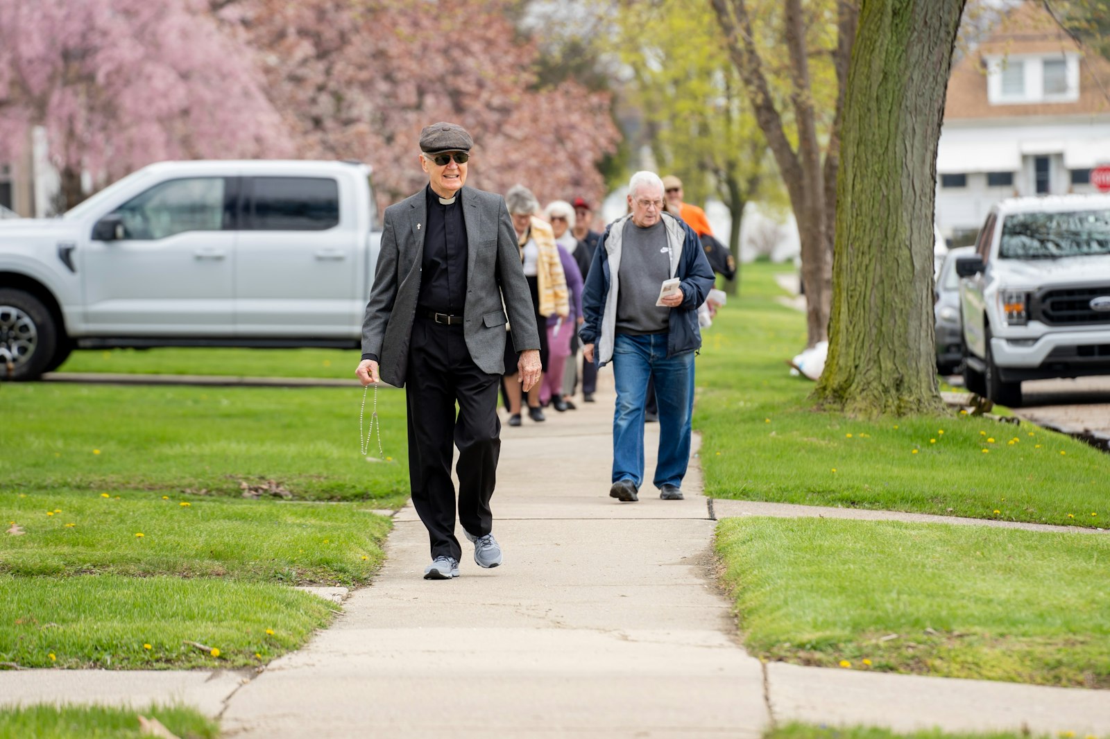 El diácono Richard Bloomfield guía a los feligreses en un paseo por la acera de un barrio de Wyandotte el 1 de mayo. Los "paseos del rosario" forman parte de la comunidad parroquial desde 2002, cuando se instalaron las "cajas del rosario".