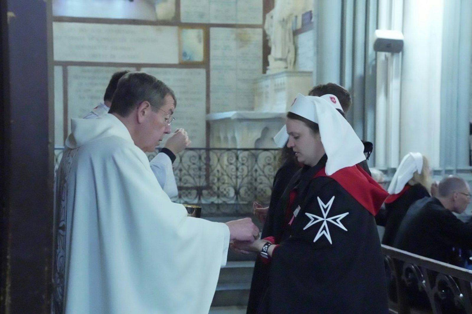 Molly Modes receives Communion from Detroit Archbishop Allen H. Vigneron during a pilgrimage this spring to Lourdes, France. Archbishop Vigneron, a member of the Order of Malta, is a frequent participant in the order's annual pilgrimage. This year, the archbishop was named Grand Cross Conventual Chaplain Ad Honorem of the order in honor of his service to the poor and sick.