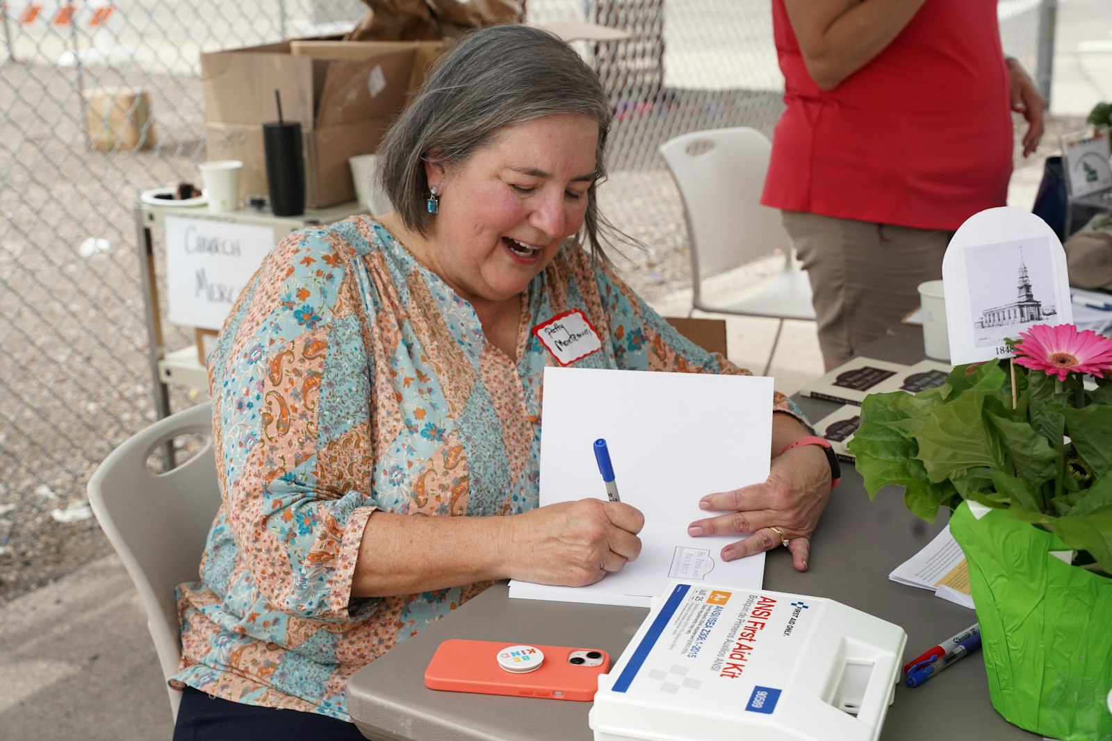 Patricia Montemurri, a Michigan Journalism Hall of Famer and former Detroit Free Press reporter, signs a copy of her "Images of America" book about SS. Peter and Paul during the parish's block party following the 175th anniversary Mass.