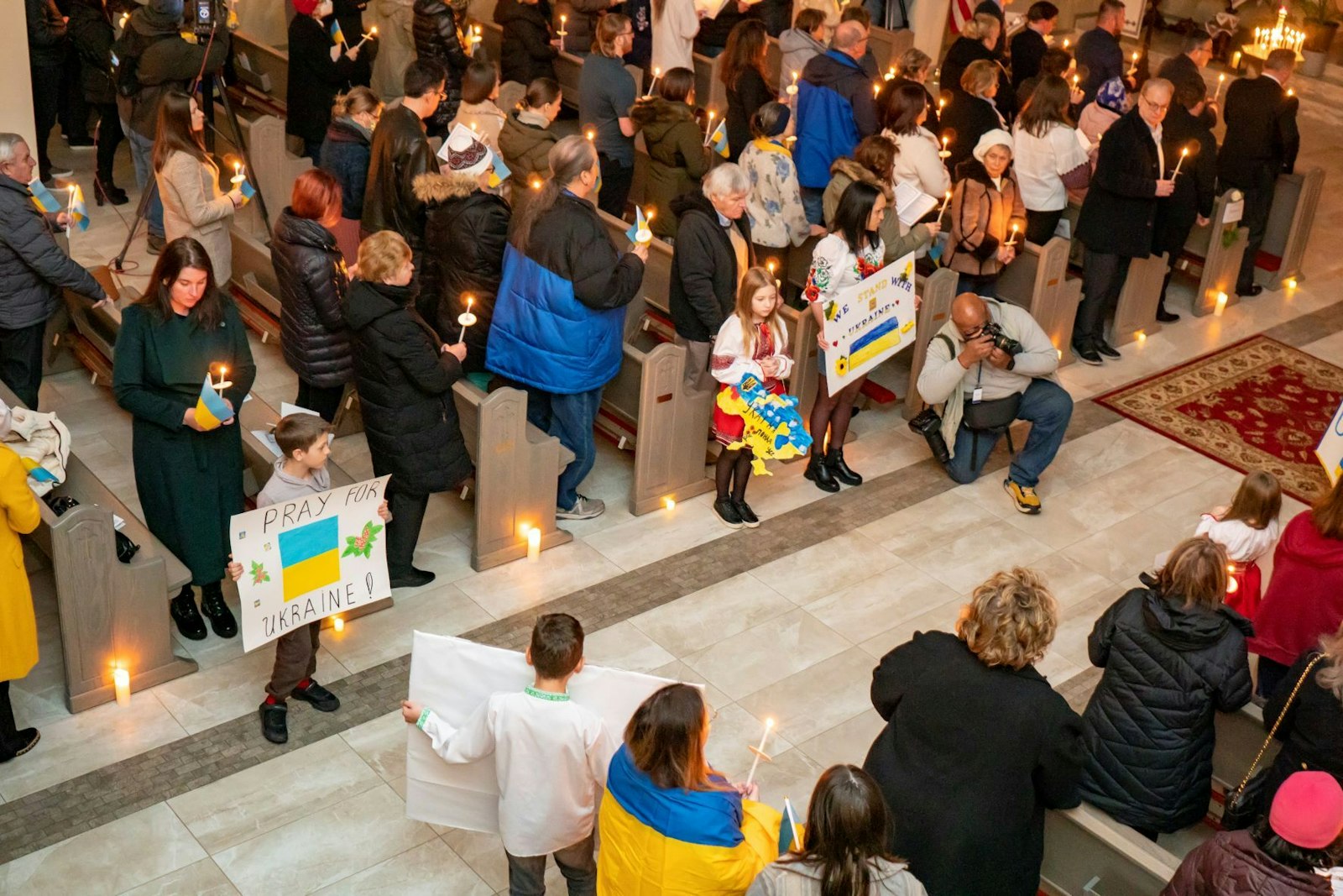 Children hold signs of support for Ukraine as parishioners hold candles during a prayer vigil Feb. 24 at St. Mary the Protectress Ukrainian Orthodox Cathedral in Southfield. (Matthew Rich | Special to Detroit Catholic)