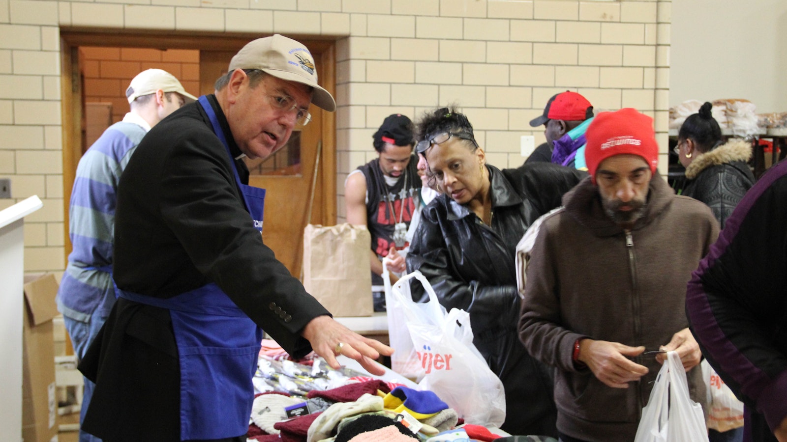 Archbishop Vigneron helps hand out hats, gloves and scarves at the Matchan Nutrition Center in Pontiac on Dec. 22, 2016. The soup kitchen, which serves hot meals to approximately 500 people every Tuesday and Thursday, is in the gym of St. Vincent de Paul Church, part of St. Damien of Molokai Parish. (Jonathan Francis | Detroit Catholic file photo)