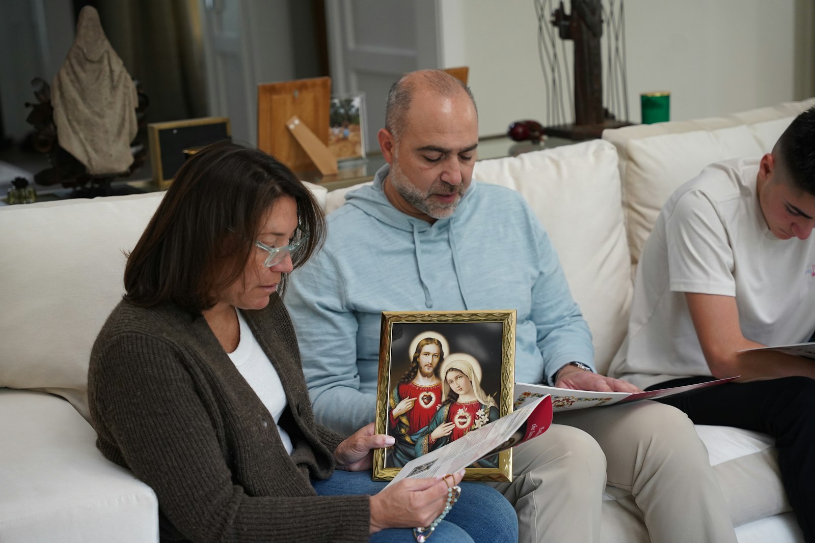 Saba Mona holds an image of the Sacred Heart of Jesus and the Immaculate Heart of Mary while reciting a prayer during the enthronement of her family's home. Mona said hearing the prayer intentions of her children and her husband, Anthony, was particularly powerful.
