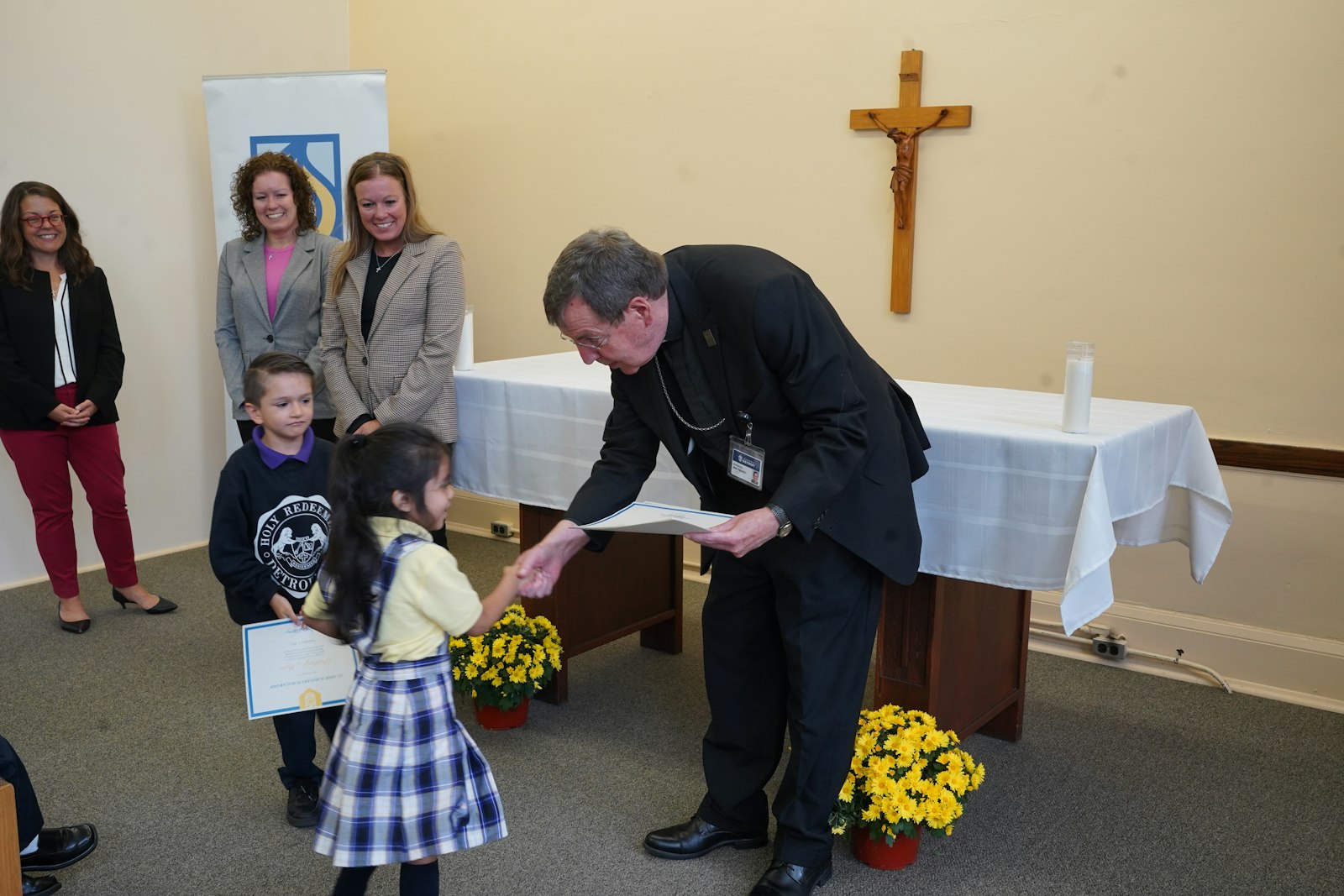 Archbishop Vigneron hands a scholarship to a Holy Redeemer student. Holy Redeemer principal Sr. Kateri Burbee, SOLT, said the school has been blessed with these scholarships as an opportunity to reach out to parishioners who want to send their children to Catholic school.