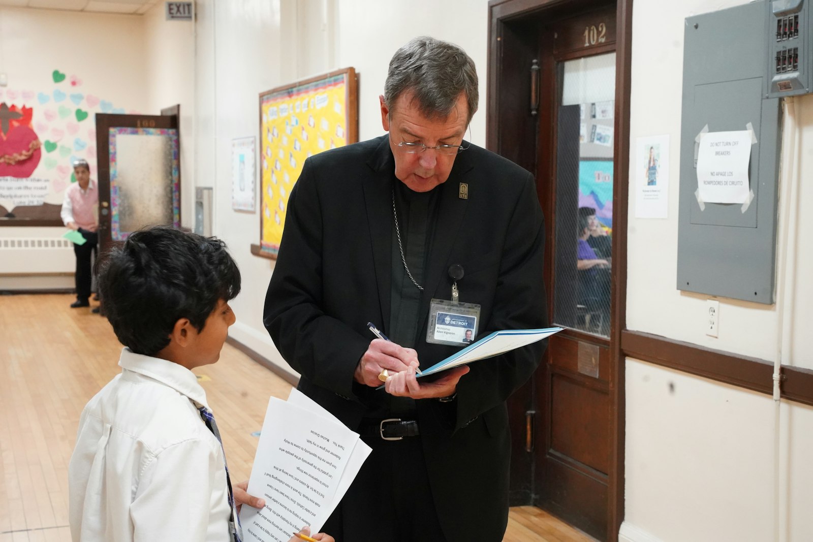 Holy Redeemer sixth-grader Mateo De Jesus Pulido gets his scholarship autographed by Archbishop Vigneron. Mateo gave a thank-you address on behalf of his Holy Redeemer classmates.