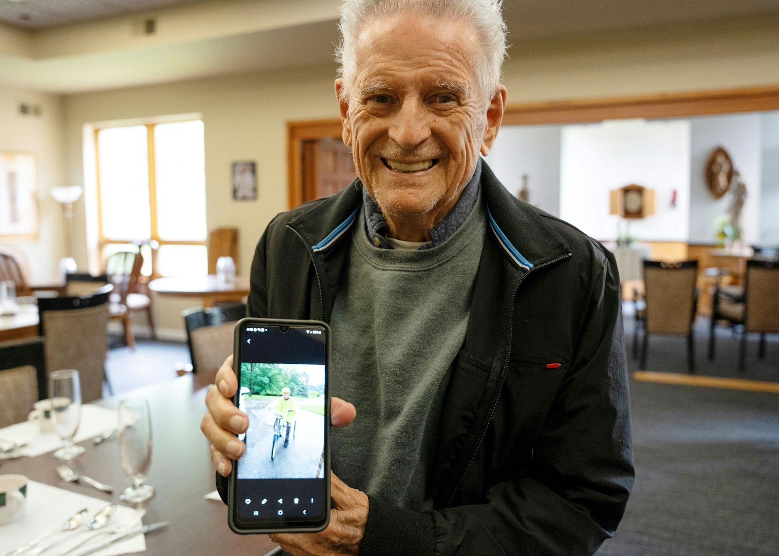 Fr. Phalen poses with a photo of himself riding a bike around the property. The Senior Clergy Village is located on the Felician Sisters Campus. Set back from the road and surrounded by nature, the 20 single-level apartment units form a half circle around the community building, which, at its center, hosts a small chapel with the Eucharist always present.