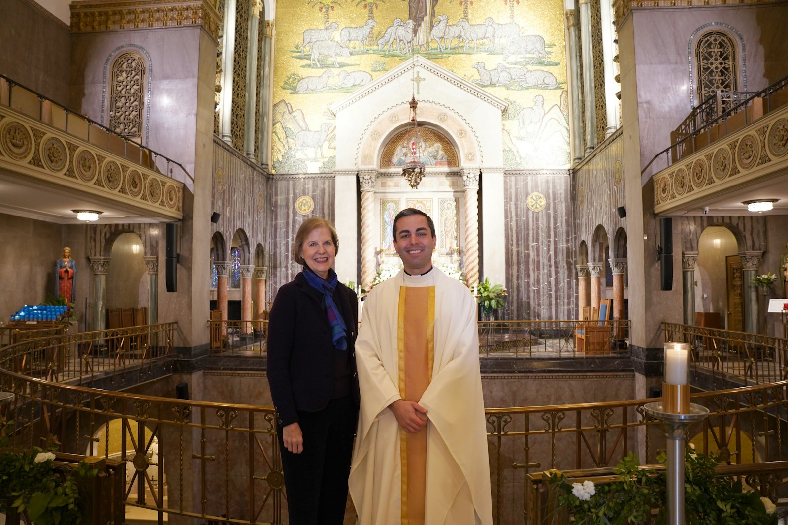 Fr. Amore stands with Hildreth Meiere Dunn, whose grandmother (Hildreth Meiere) designed the mosaic of Christ the Good Shepherd that’s behind St. Aloysius’ high altar.