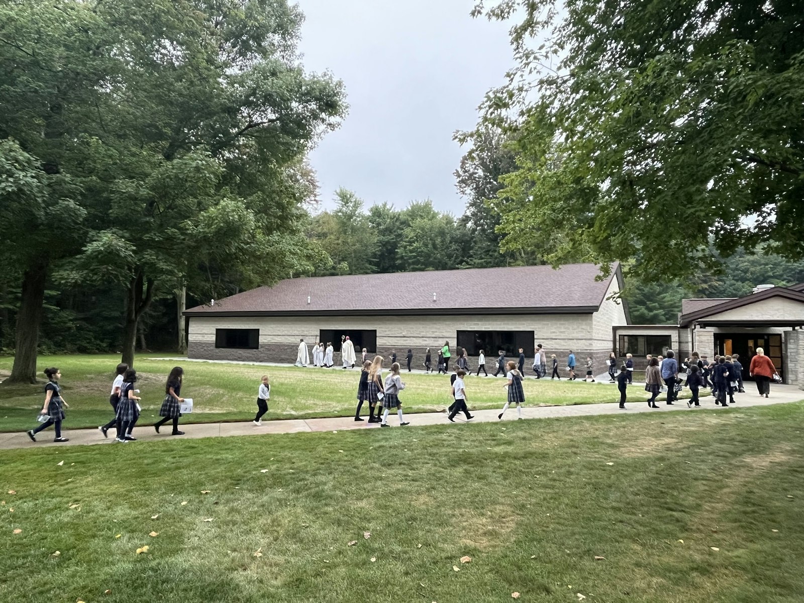 Students walk from the parish, where Bishop Fisher celebrated Mass, to the new school addition on Sept. 6.