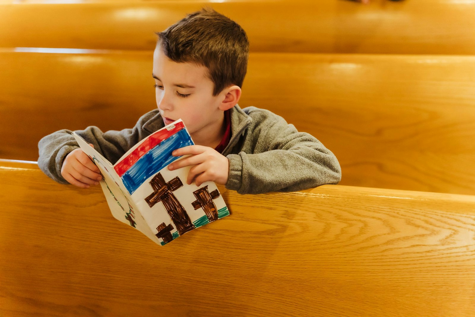 Un estudiante de la Escuela St. Isaac Jogues lee un libro en los bancos después de una misa escolar. Las nuevas familias de St. Isaac Jogues dicen que han quedado impresionadas por la cultura de fe de la parroquia y la escuela.