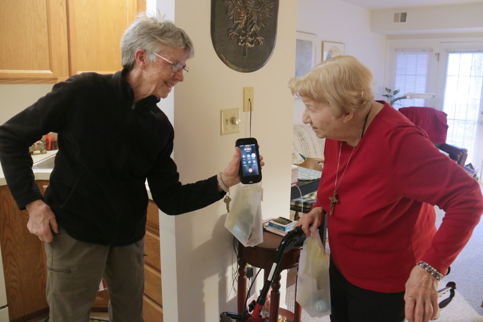 Therese Terns, left, a St. Kateri volunteer, arranges a phone call between Josephine Demps and St. Kateri's pastor, Fr. Terry Kerner, who called to check in on Demps and offer his Easter wishes.