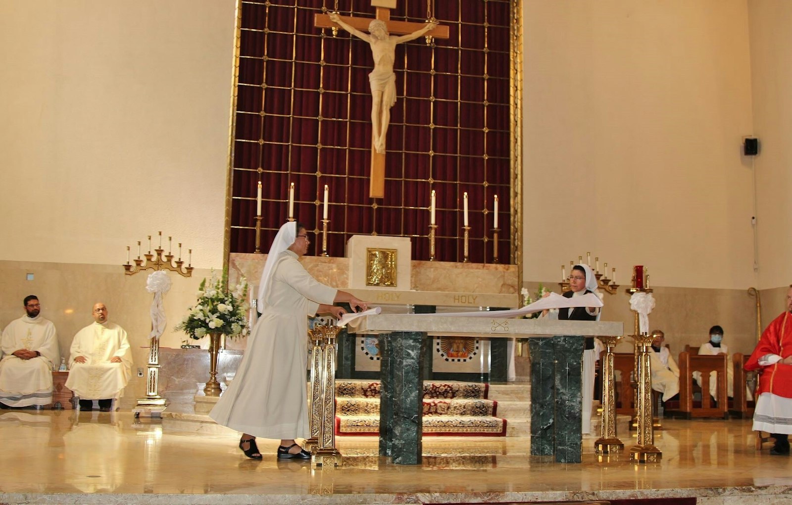 Carmelite Sisters of St. Joseph dress the altar after it is consecrated during Mass on Aug. 28. The new altar ties the traditions of the past and the old Tridentine high altar with the reforms of the Second Vatican Council and vision of the church moving forward, Northeast Macomb Family of Parishes moderator Fr. John Maksym said.