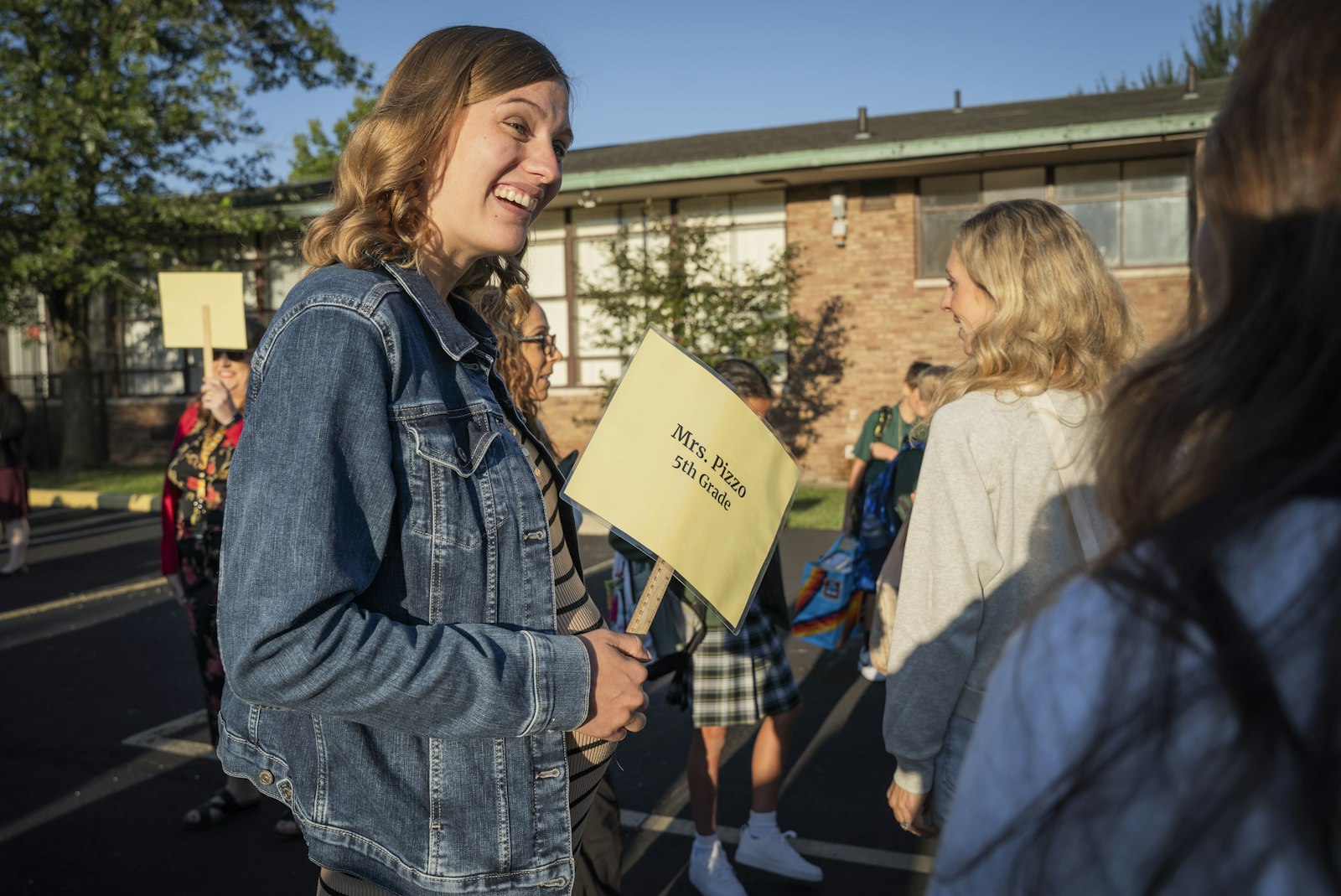 La docente de quinto grado de St. Pius X, Megan Pizzo, saluda a su nueva clase en el estacionamiento de la escuela antes de comenzar el nuevo año académico.