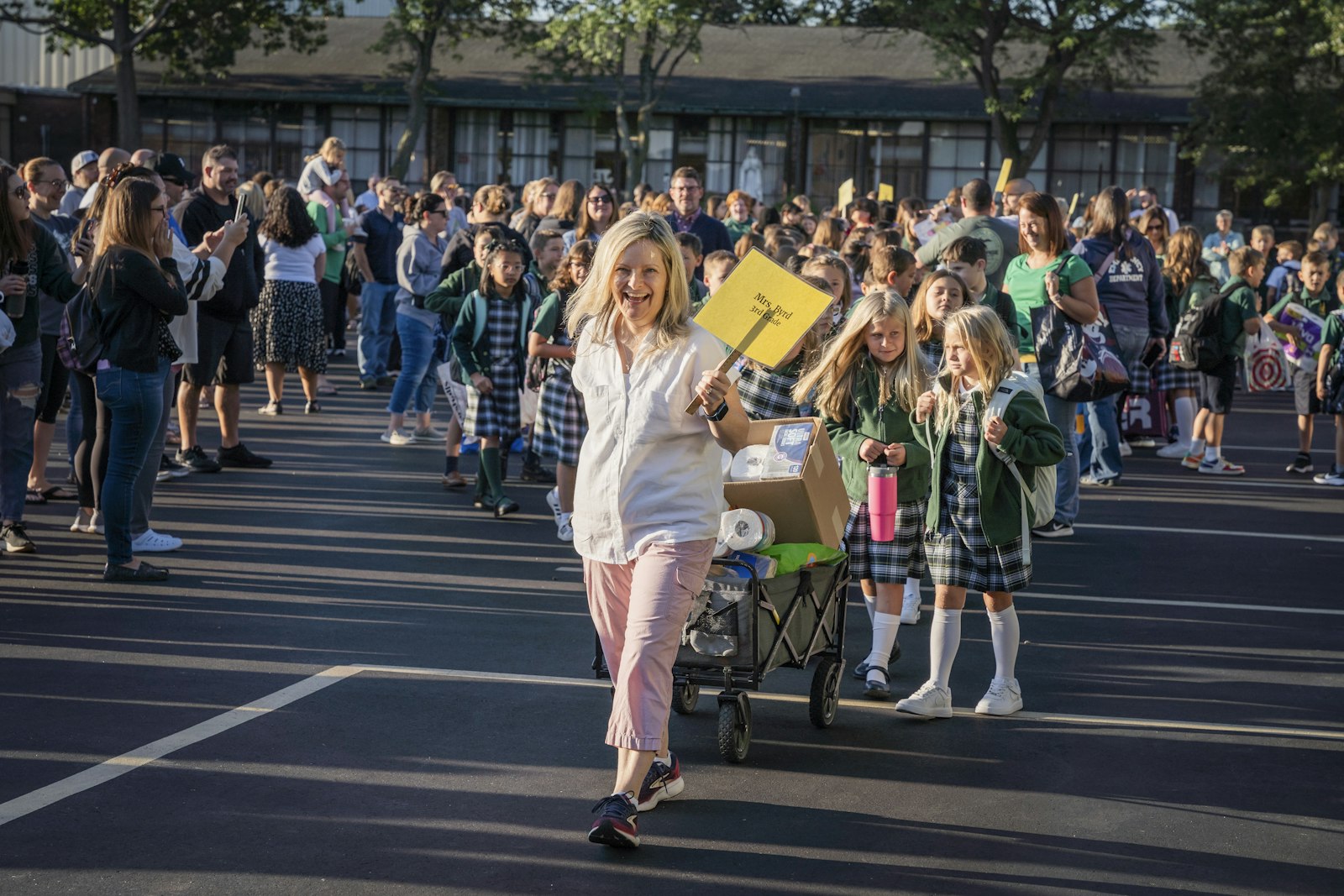 Third-grade teacher Elizabeth Byrd leads her class into the school building, with classroom supplies in tow.