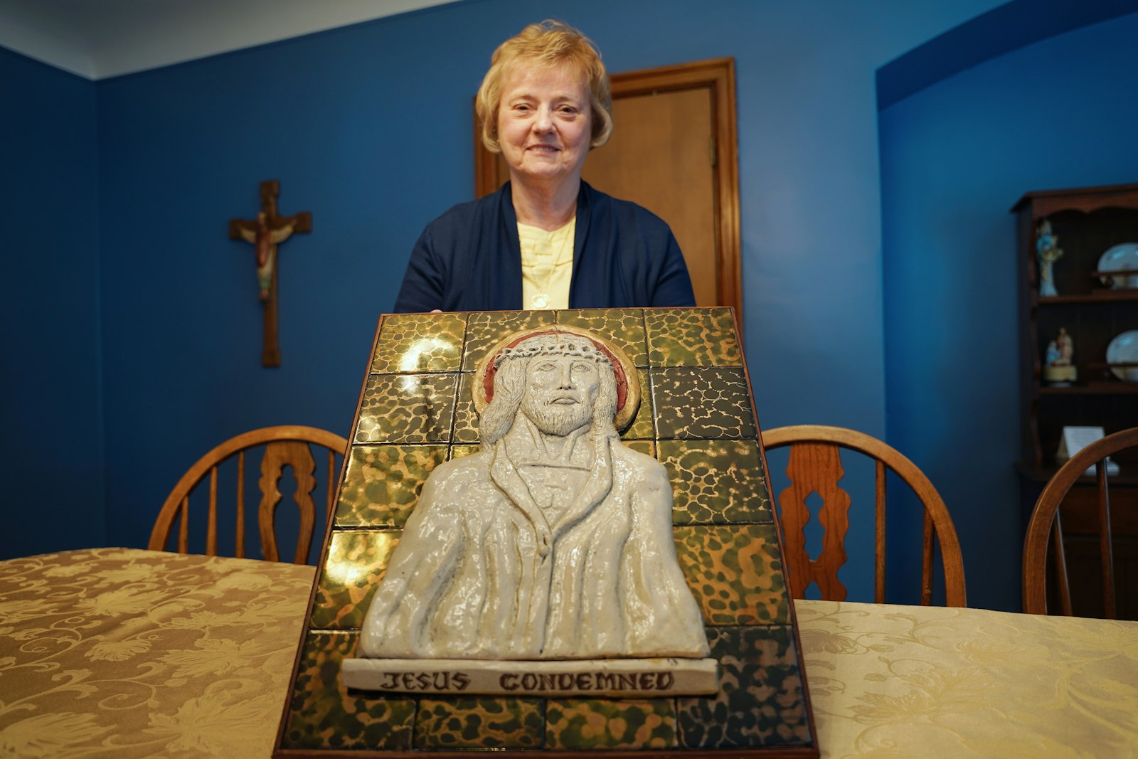 Christine Smith holds up the replacement First Station of the Cross her husband, Kirby, made after the original first station was stolen from St. Augustine Parish in Richmond in the 1990s. In the spring of 2023, the parish received a phone call from Leonard St. Pierre of the Our Lady of Fatima Shrine in Riverview, saying he had the original station in a story that has plenty of twists and turns. (Photos by Daniel Meloy | Detroit Catholic)