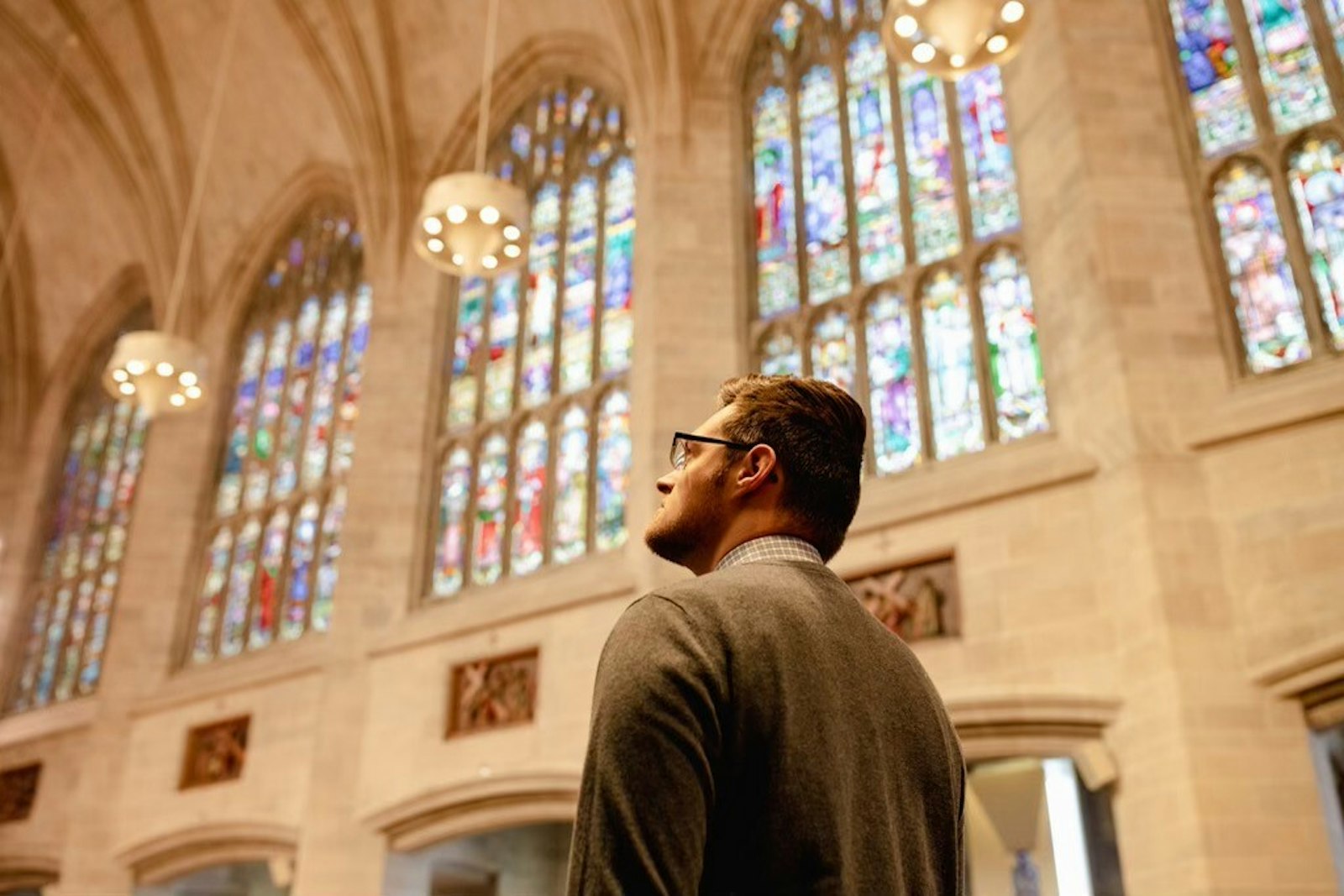 A man gazes up at the stained-glass windows inside the Cathedral of the Most Blessed Sacrament during the Mass of Suffrage for Pope Benedict XVI.
