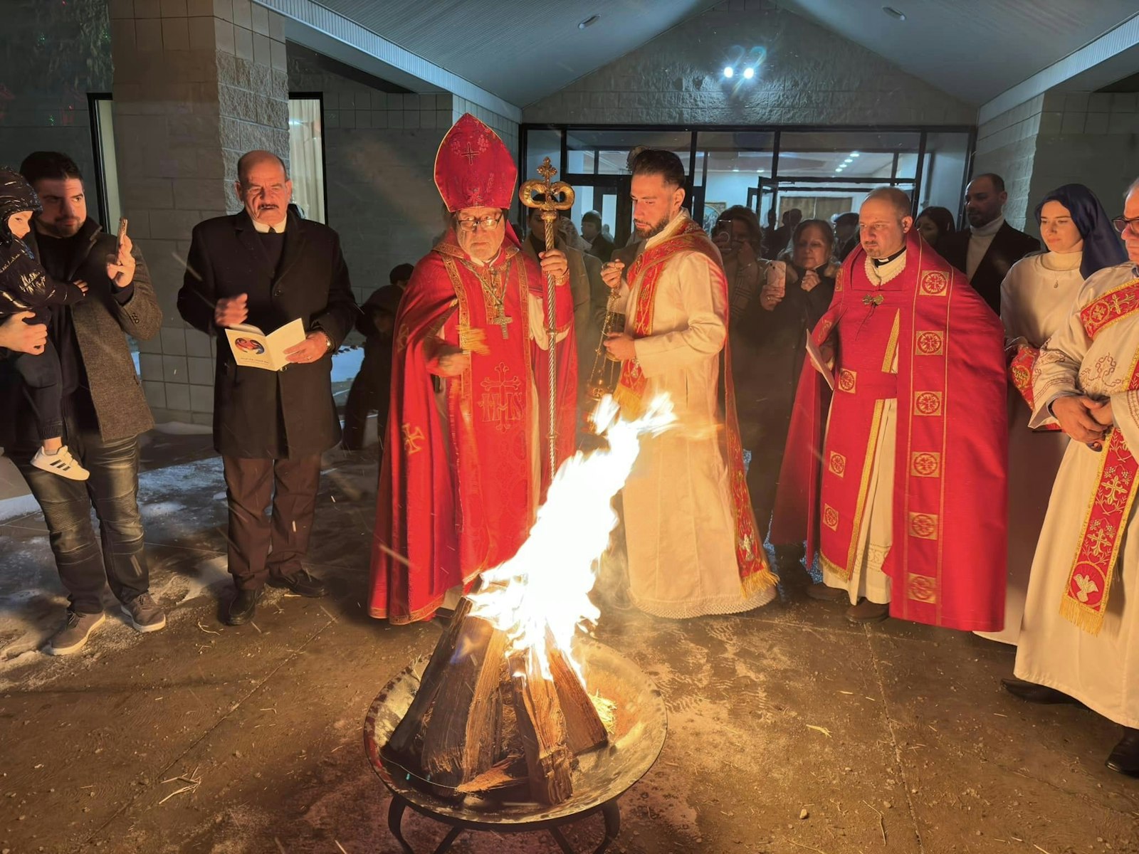 El obispo Habash ora sobre el fuego navideño fuera de la Catedral Católica Siria de St. Toma durante una liturgia navideña. Iglesias como St. Toma son el hogar de un gran número de refugiados iraquíes y sirios, cuya fe frente a la persecución inspira a la comunidad, dijo el obispo Habash. (Cortesía de la Catedral Católica Siria de St. Toma)