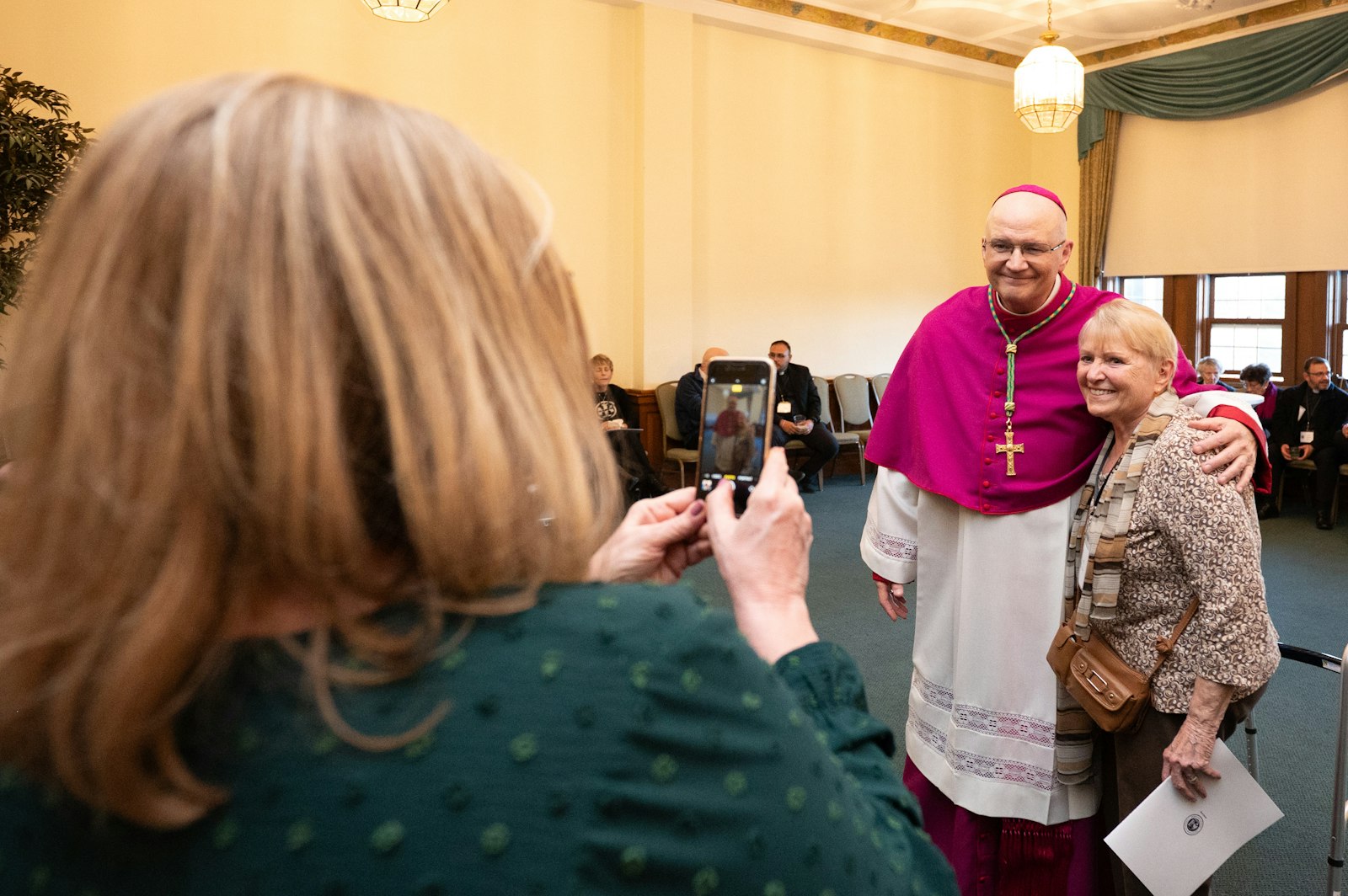 Archbishop Weisenburger takes photos during a reception with clergy, religious and members of the lay faithful March 17 following a vespers service at Sacred Heart Major Seminary. (Tim Fuller | Special to Detroit Catholic)