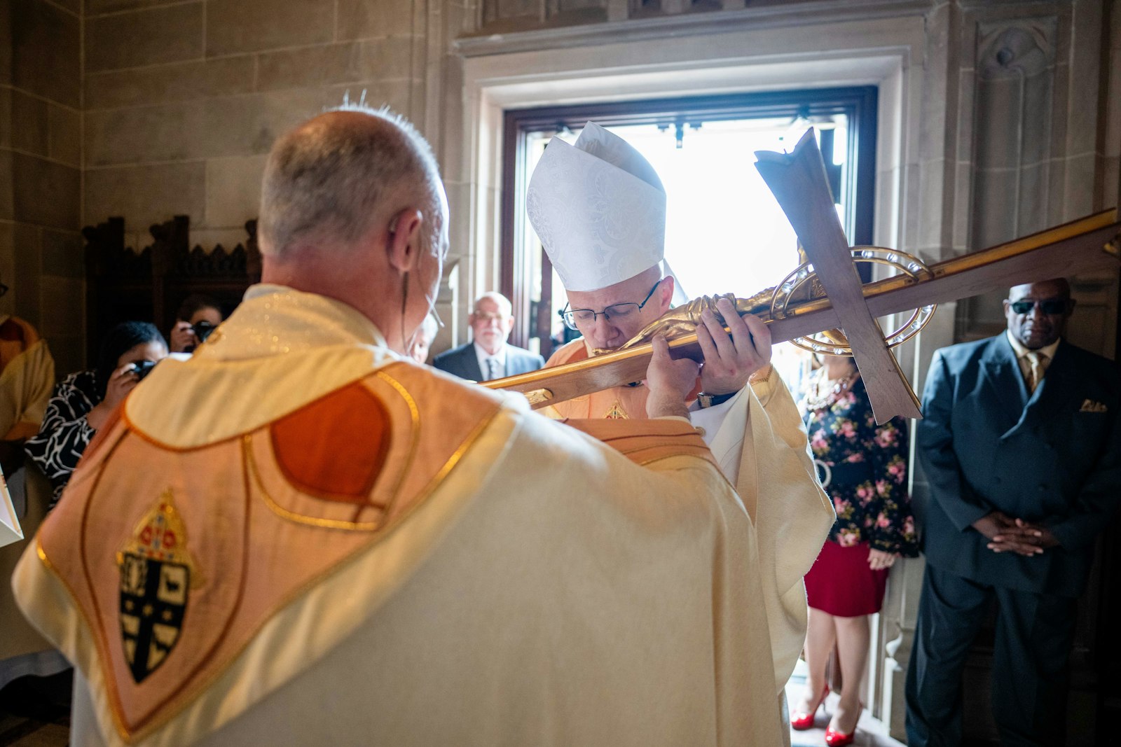 Archbishop Edward J. Weisenburger venerates a crucifix given to him by cathedral rector Fr. J.J. Mech as he enters the Cathedral of the Most Blessed Sacrament at the start of his installation Mass on March 18. (Tim Fuller | Detroit Catholic)