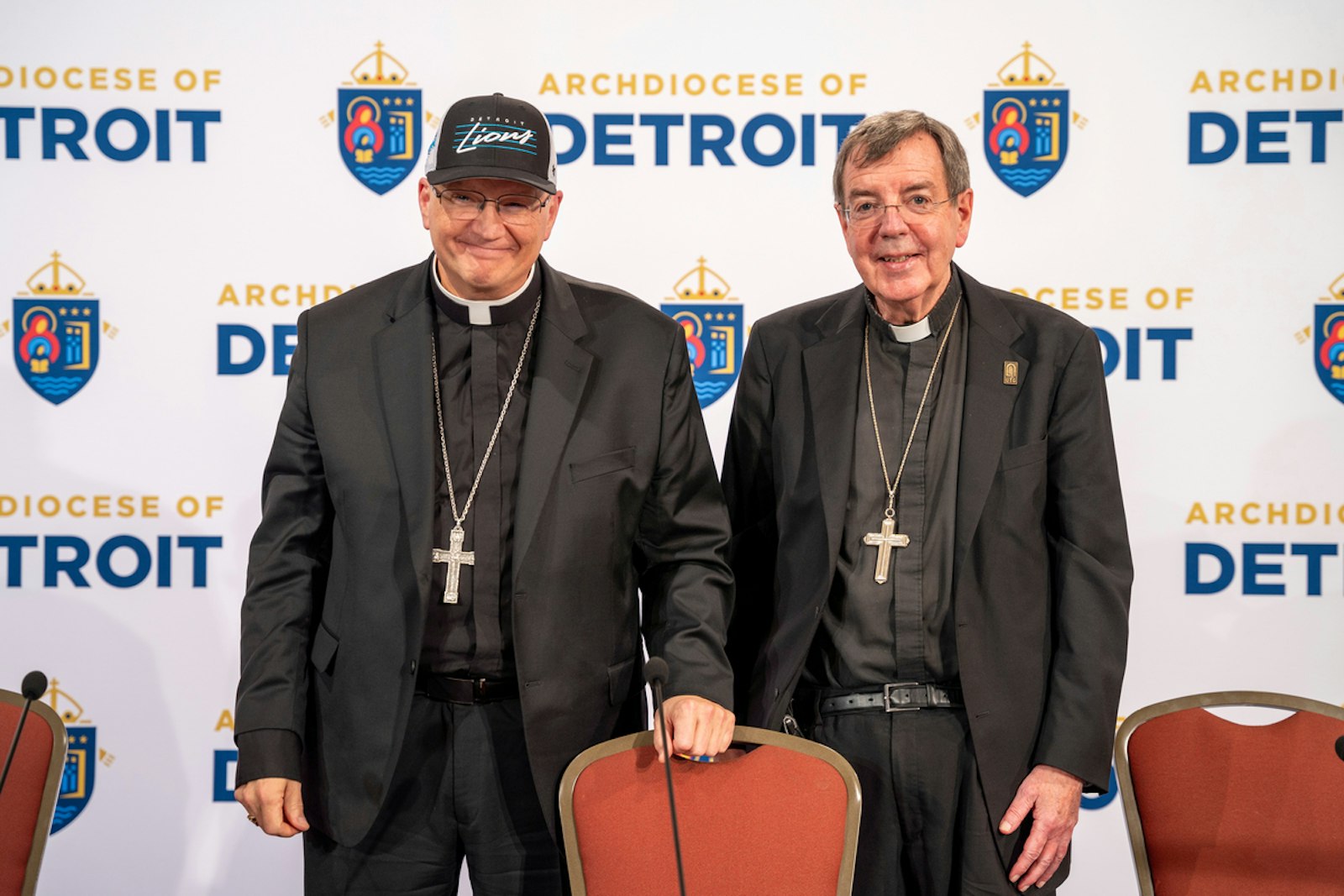 Archbishop-designate Edward J. Weisenburger dons a Detroit Lions hat Feb. 11 as he poses for photos next to Detroit Archbishop-emeritus Allen H. Vigneron during a press conference at Sacred Heart Major Seminary announcing Archbishop-designate Weisenburger as the next archbishop of Detroit. (Valaurian Waller | Detroit Catholic)