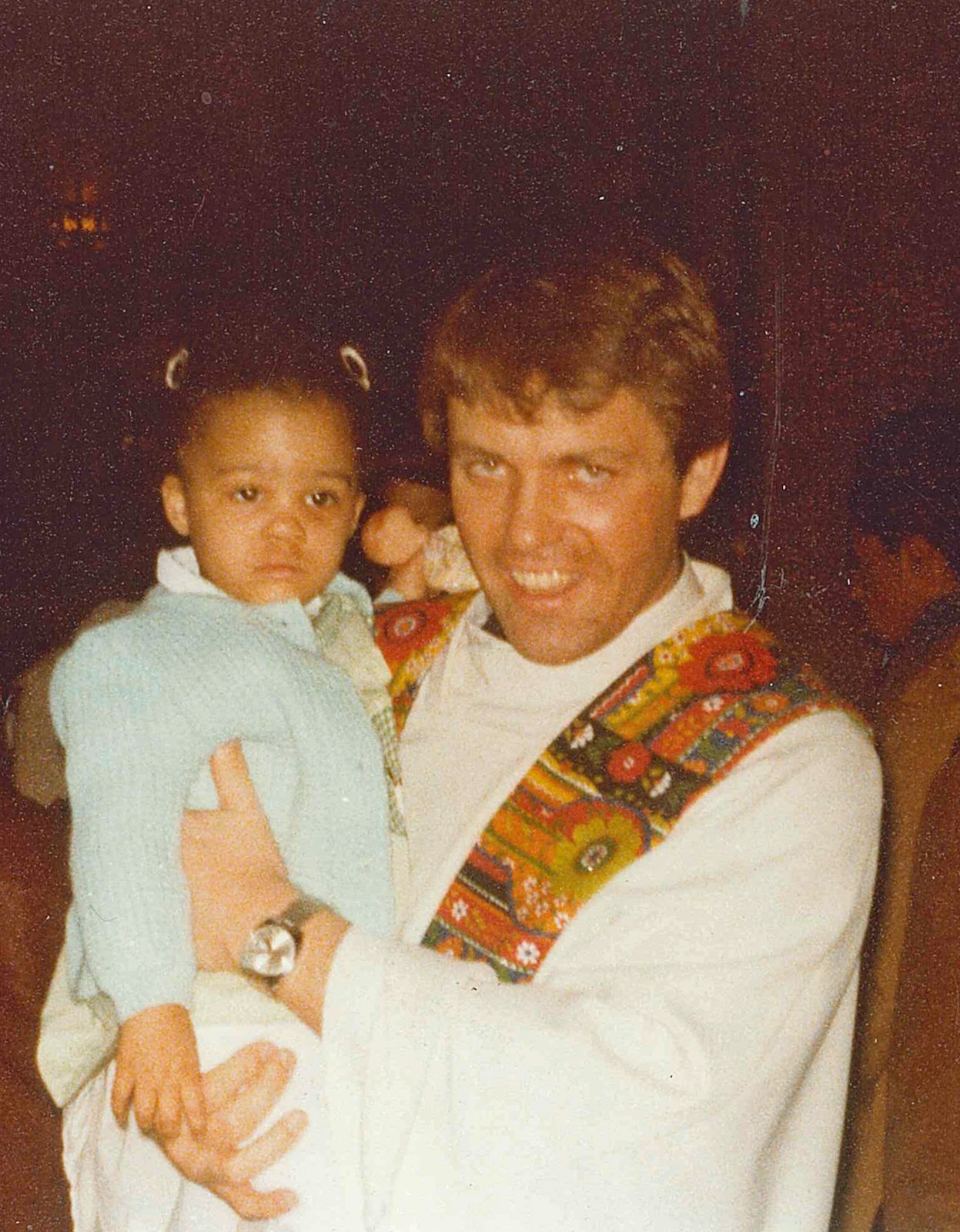 Fr. Donald Hanchon, shortly after his ordination, holds a child at the Cathedral of the Most Blessed Sacrament, his first assignment as a priest. (Detroit Catholic file photo)