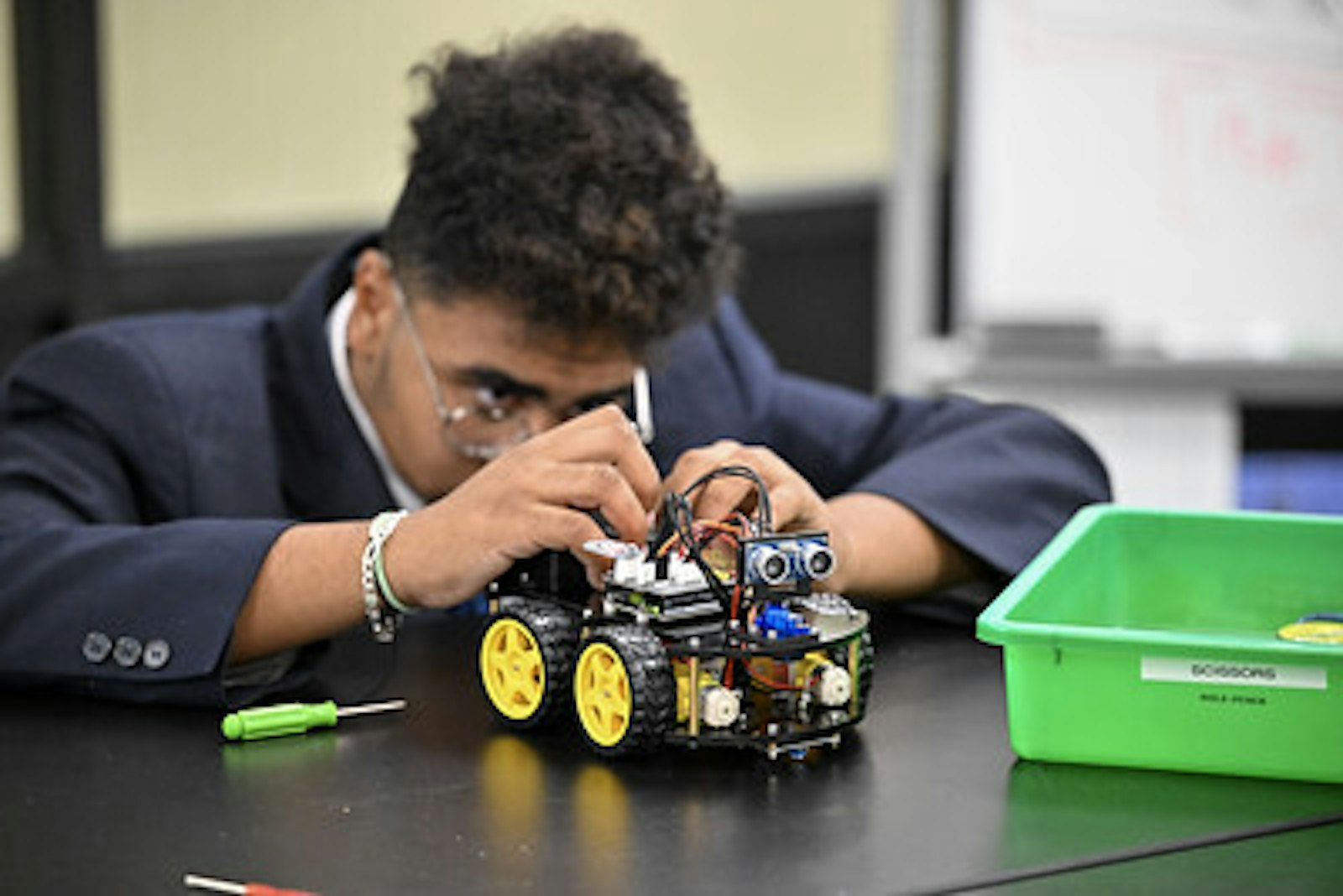 Freshman Jack P. makes adjustments to his robot during an Intro to Robotics course.
