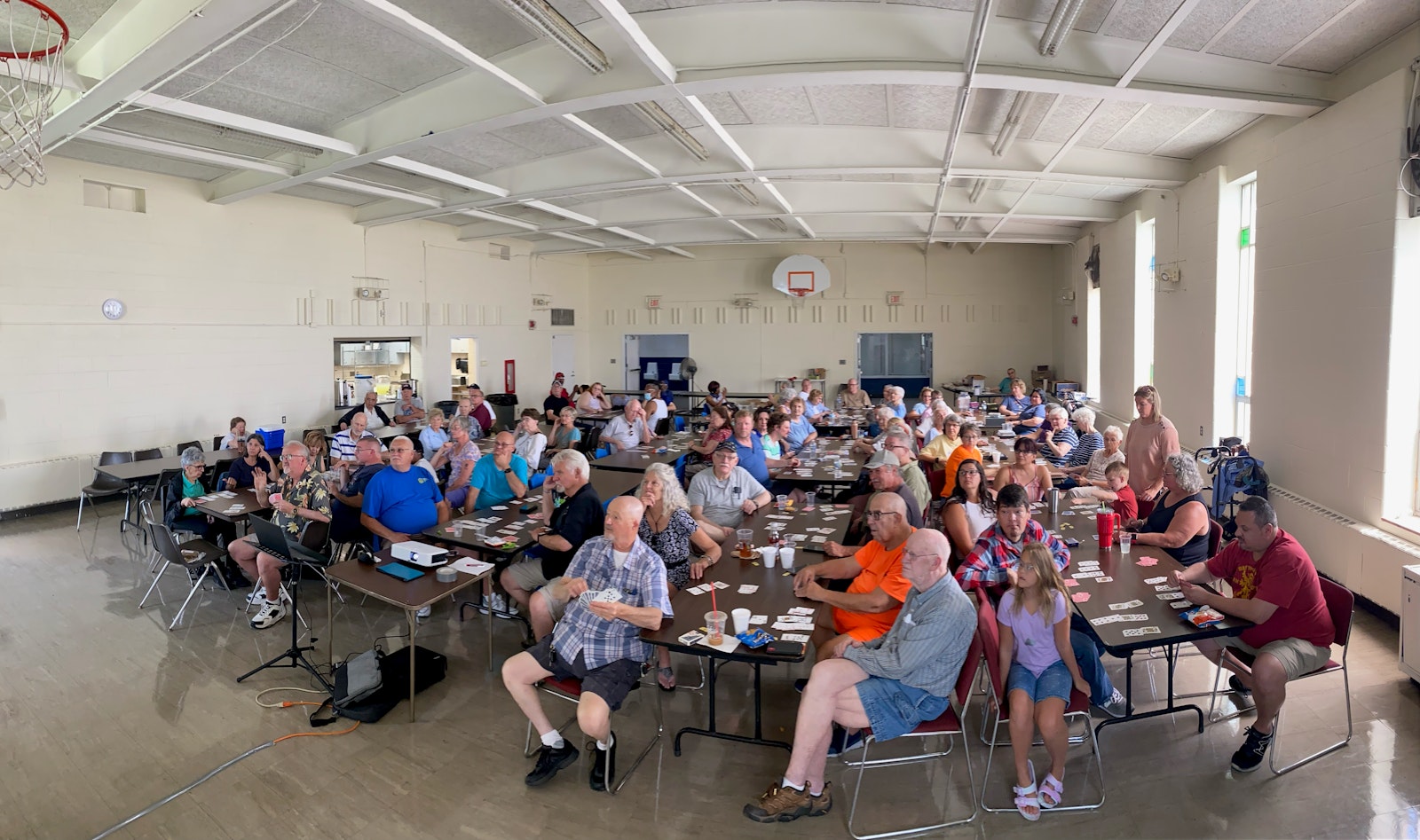 La comunidad disfruta de un picnic y juego de cartas en el gimnasio de la Holy Innocents St. Barnabas Church’s en julio de 2023 (Foto por Aaron Langevin)